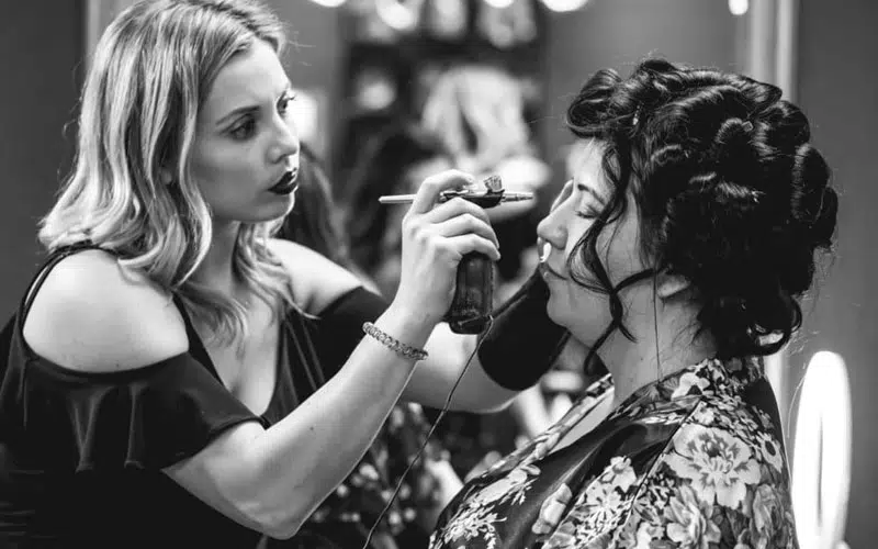 Bride getting makeup done black and white