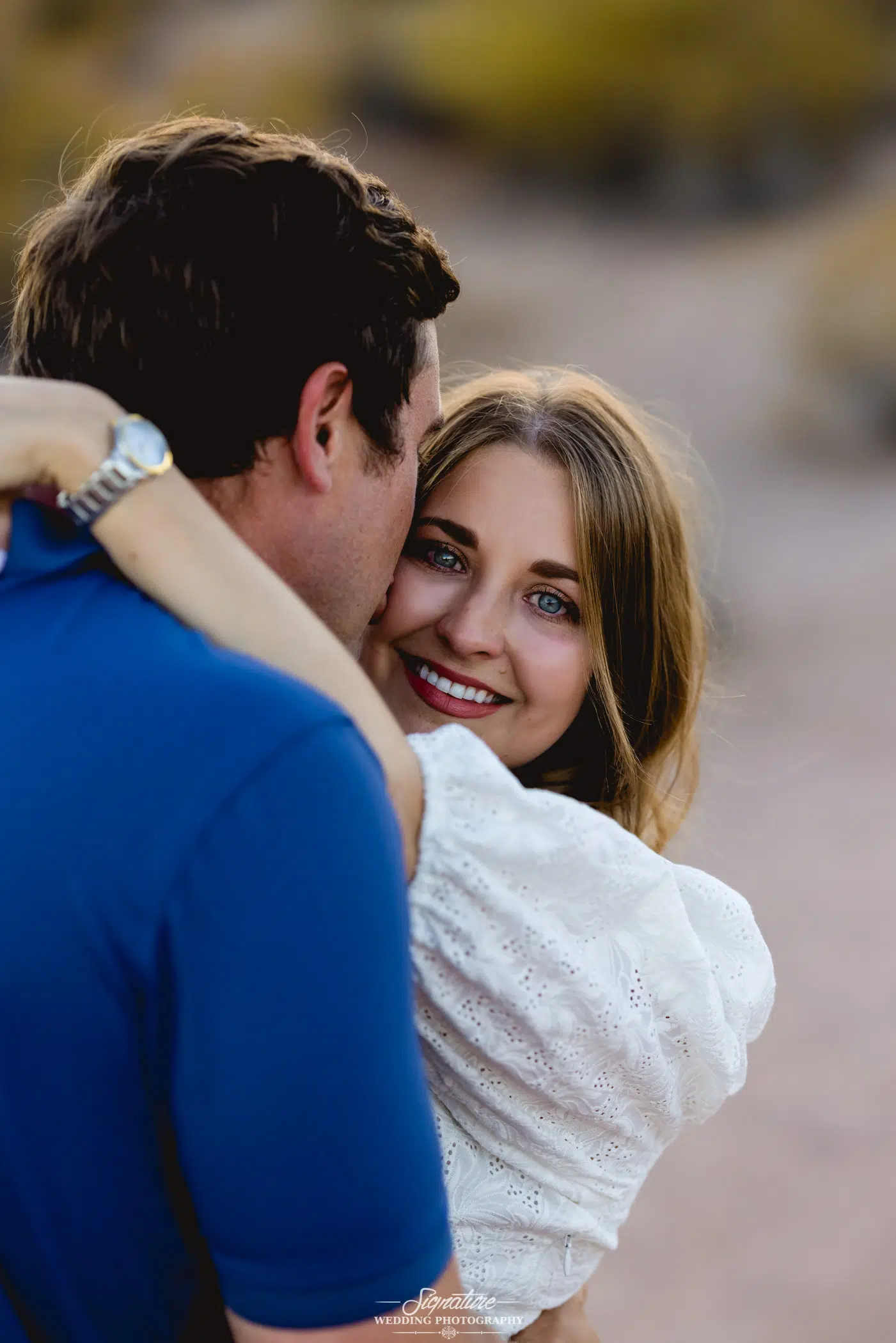 Man kissing woman on cheek while she smiles at camera