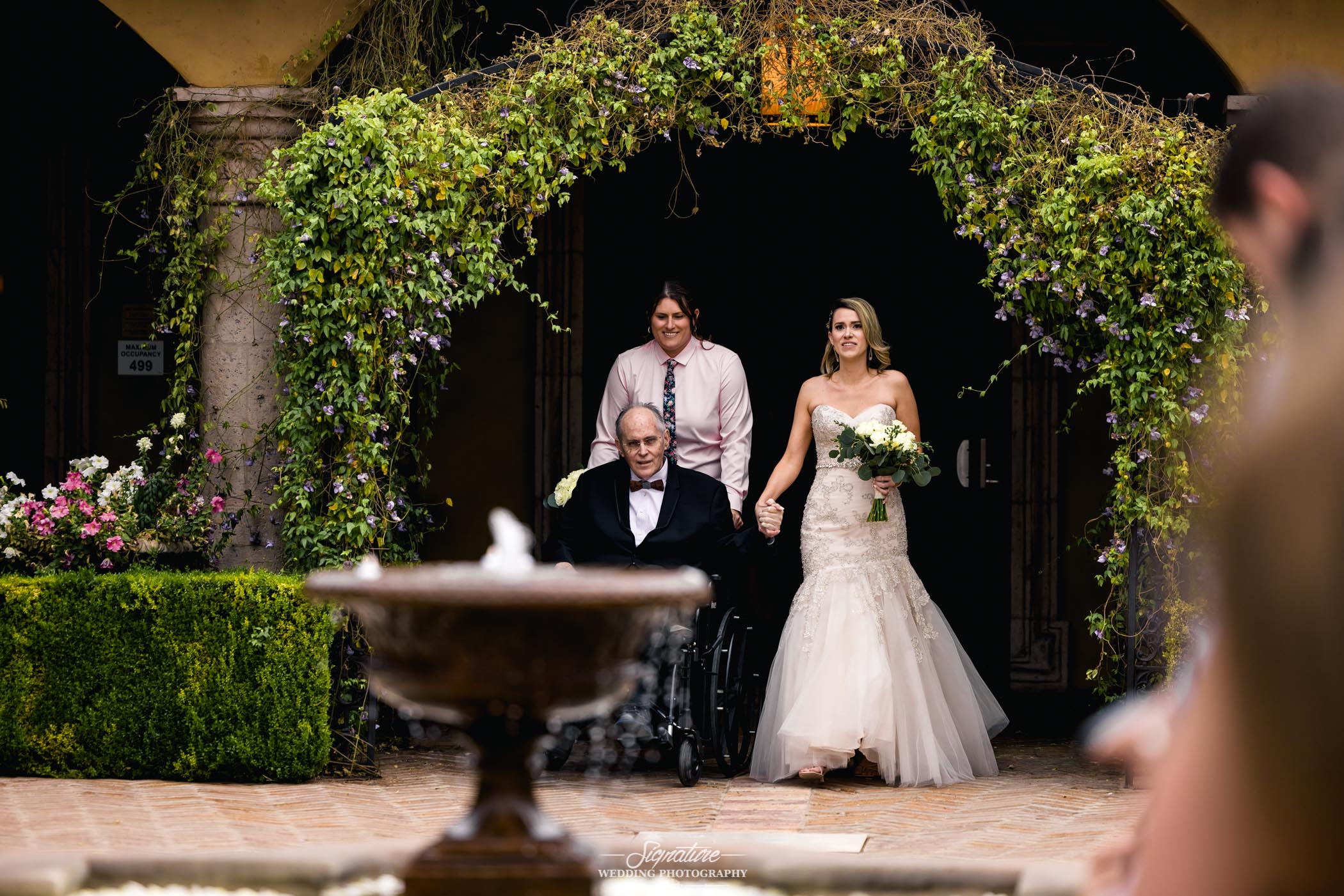 Bride walking down aisle with patriarch in wheelchair