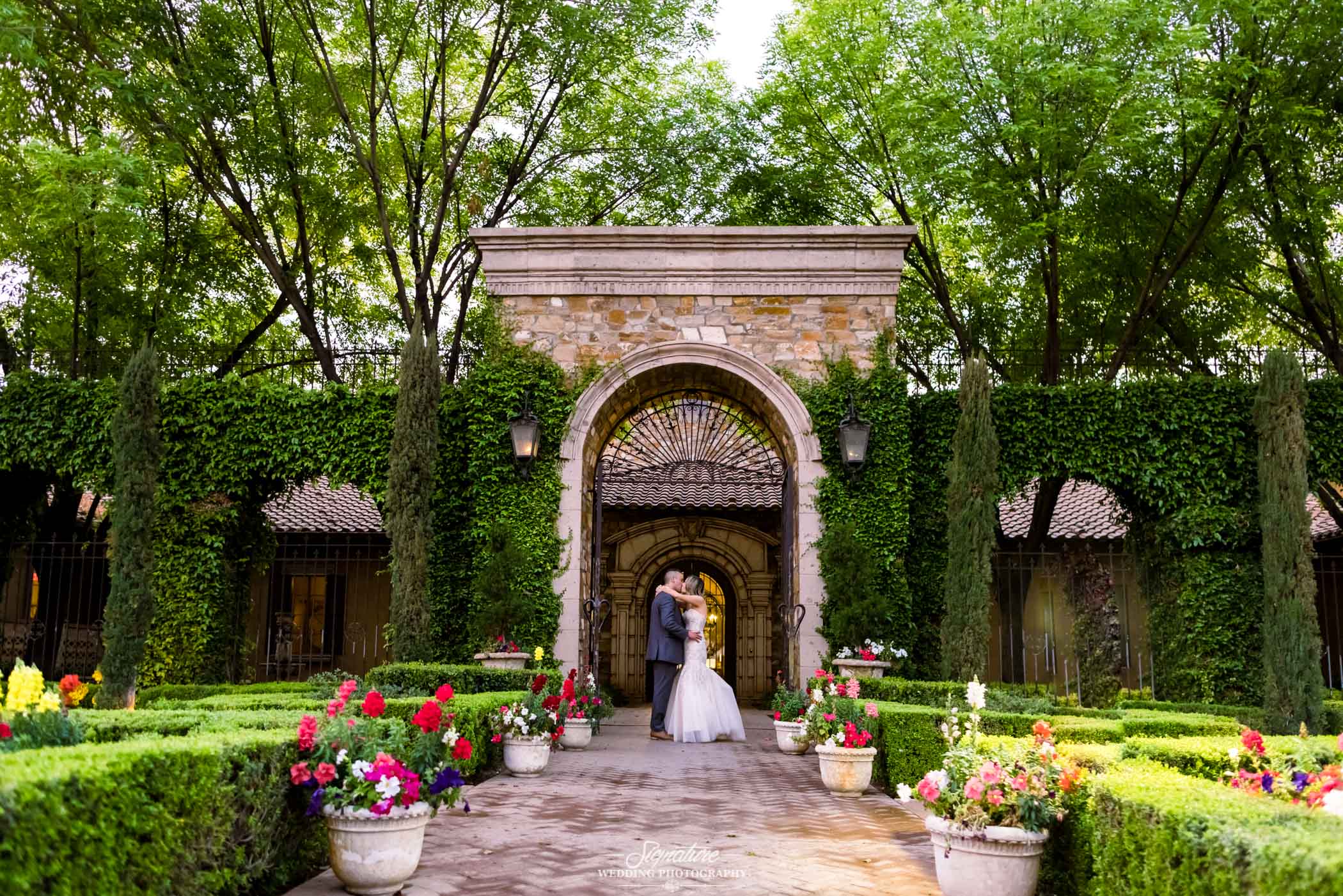 Bride and groom kissing under archway in garden