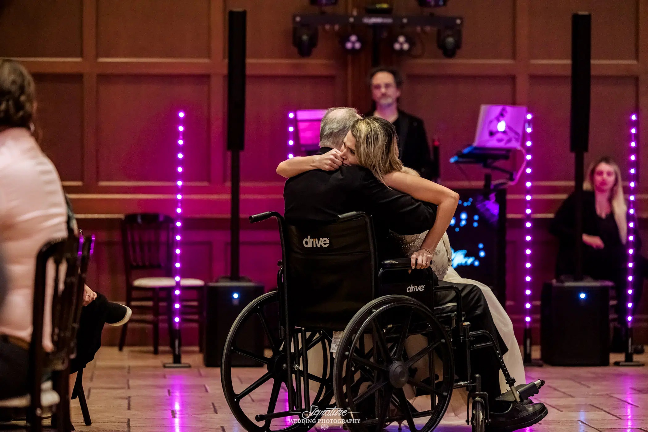 Bride sitting in patriarch's lap in wheelchair