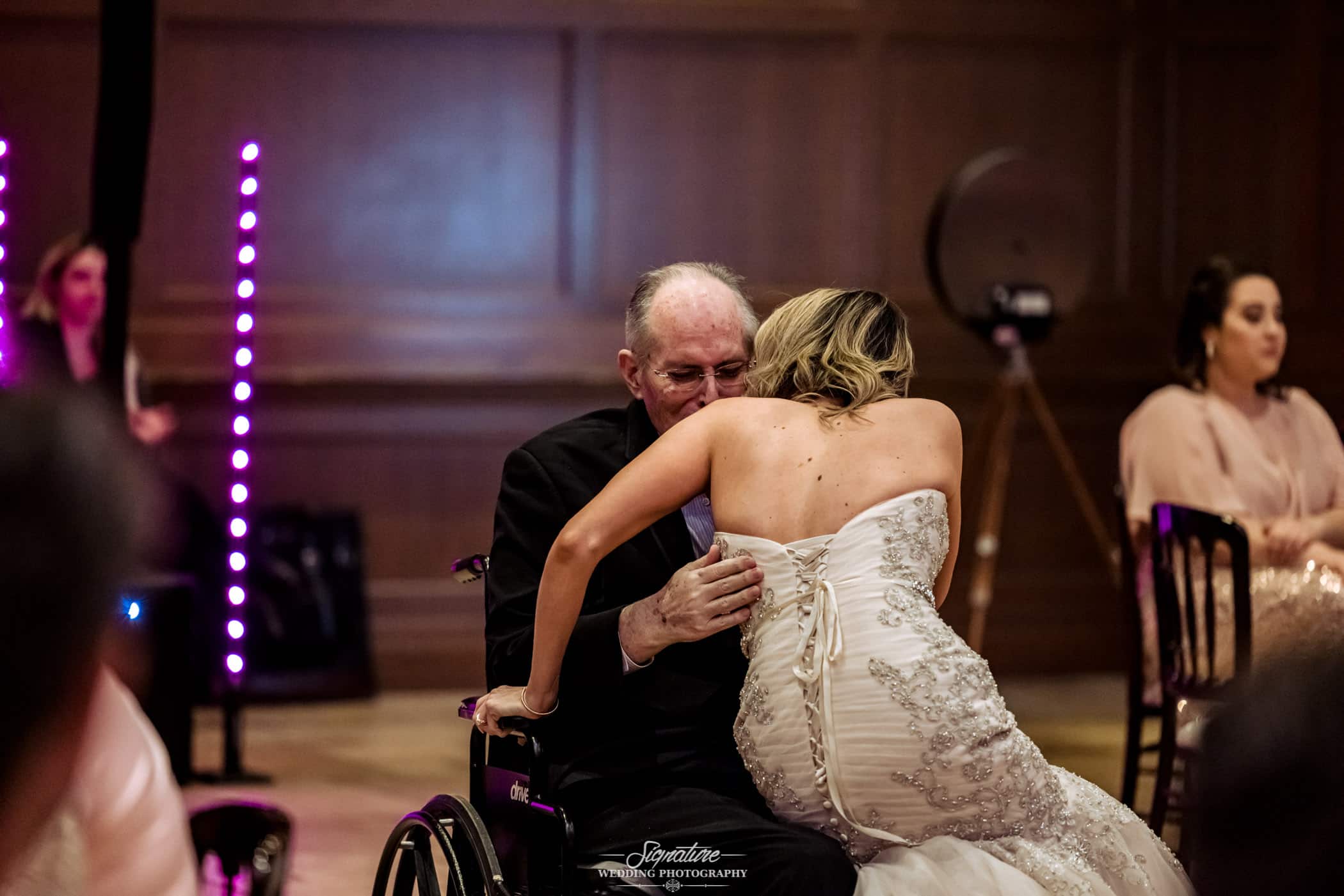 Bride sitting in patriarch's lap in wheelchair