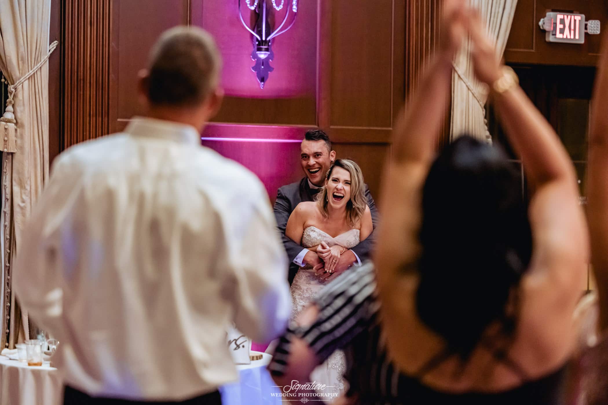 Groom hugging bride from behind at reception