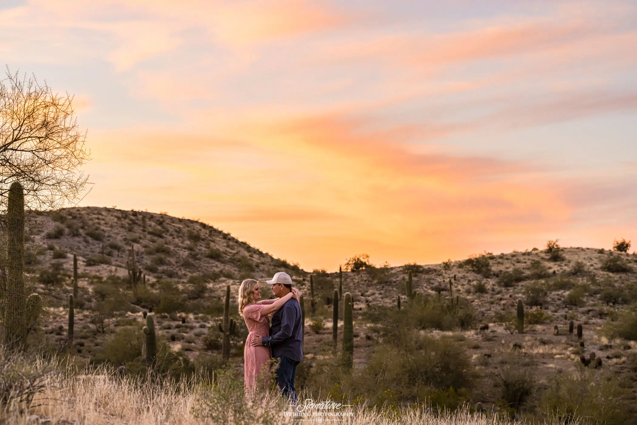 Couple with arms around each other in desert at sunset