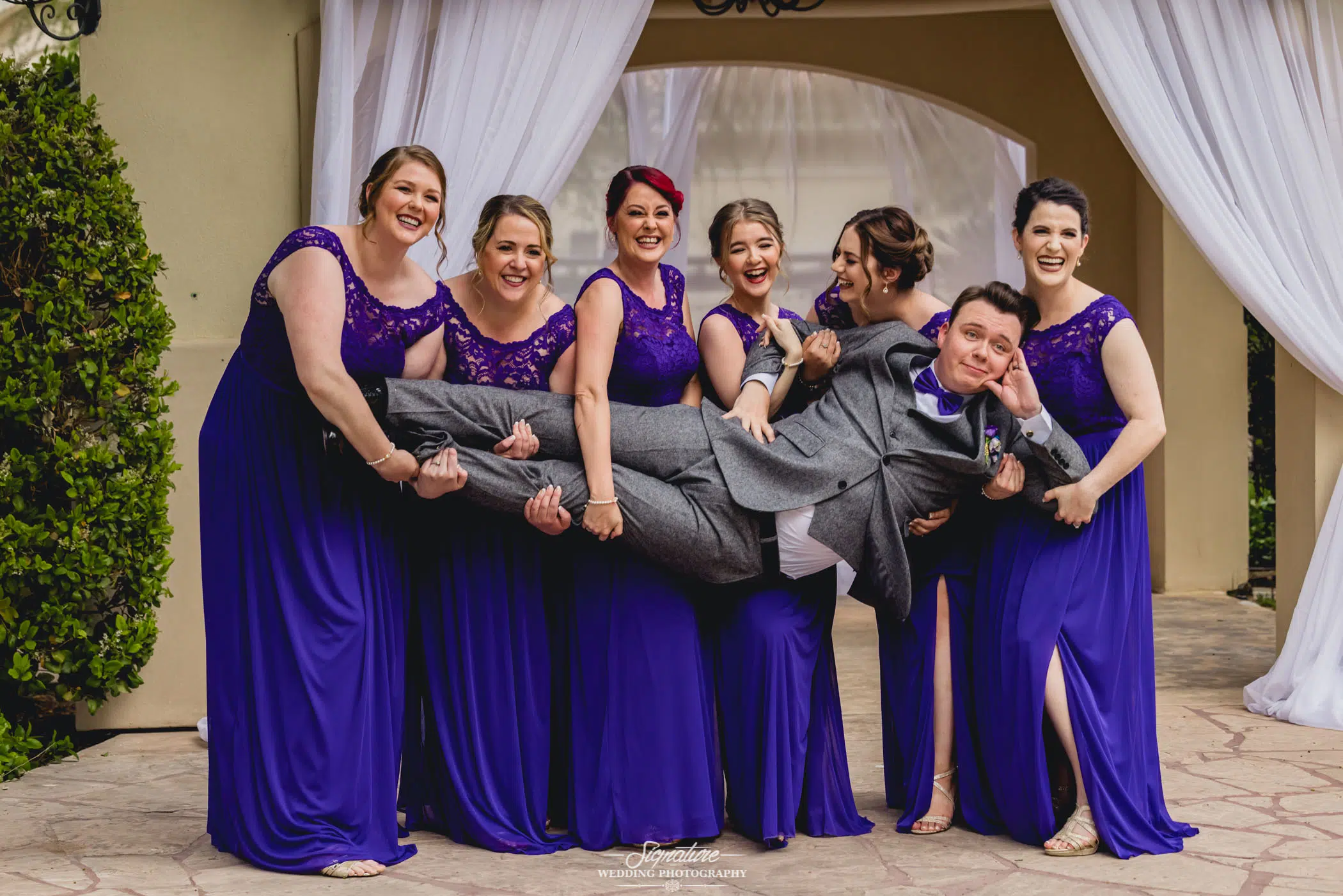 Bridesmaids holding up groom