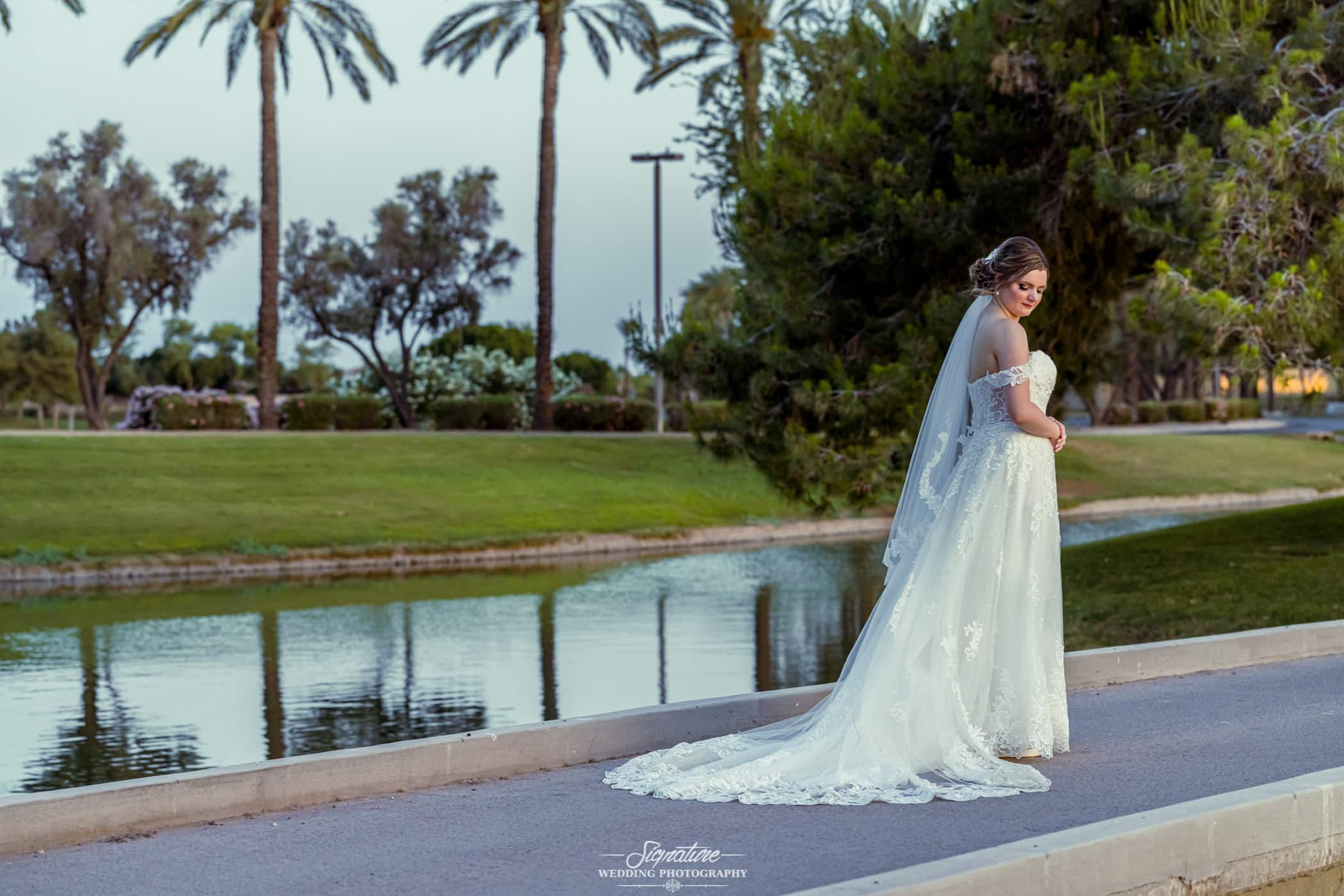 Bride standing in front of pond looking down