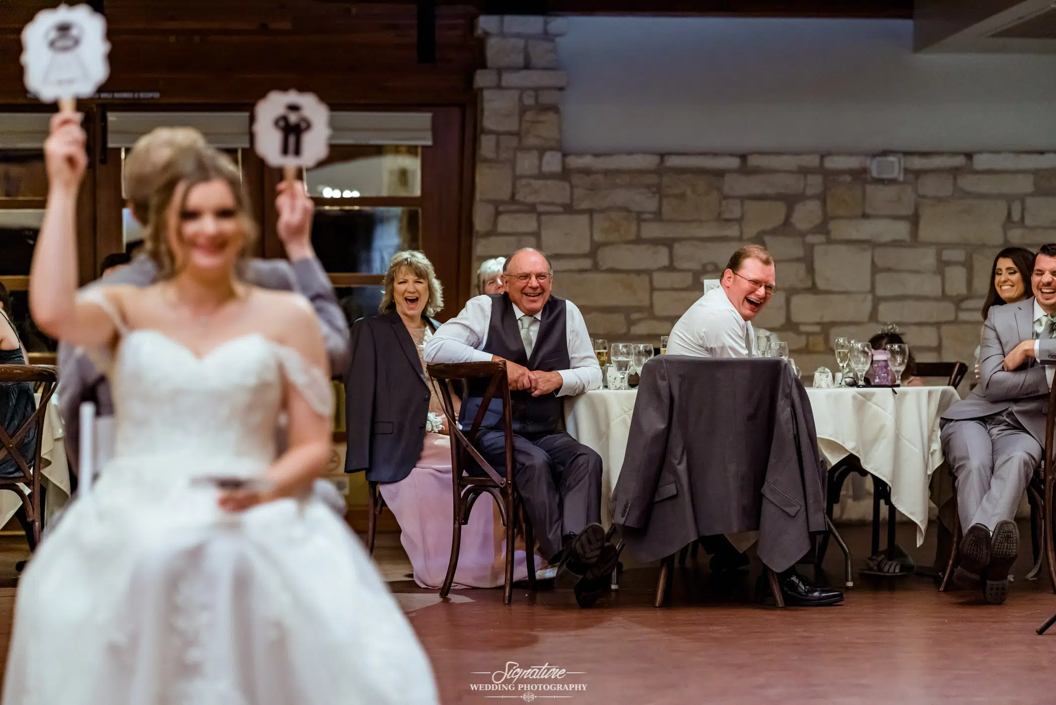 Guests laughing at bride and groom playing game at reception
