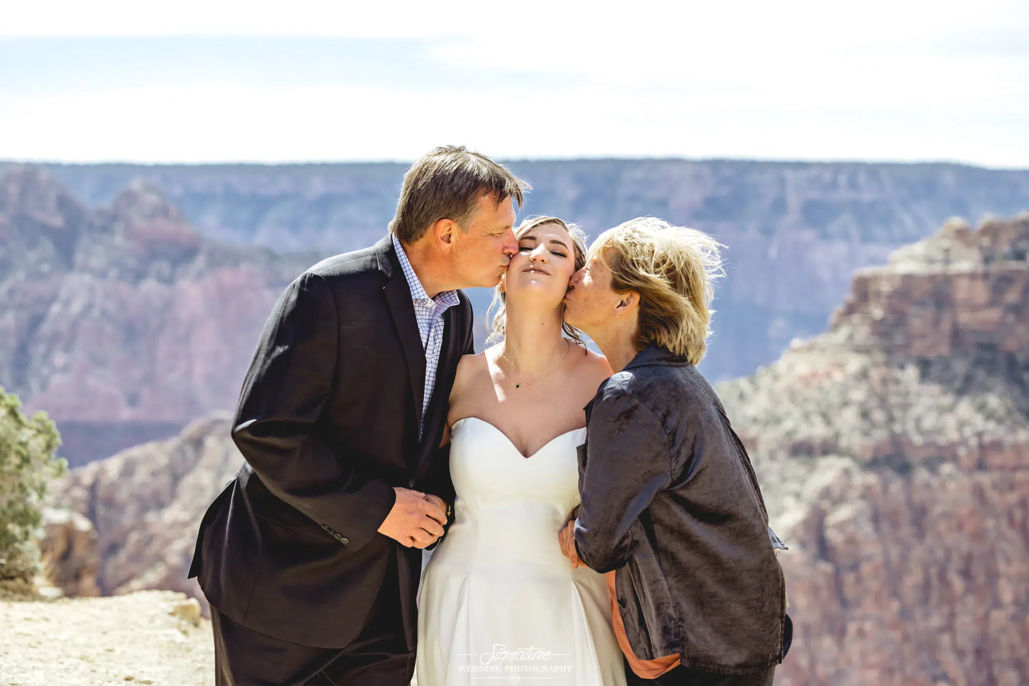 Matriarch and patriarch kissing bride on cheeks