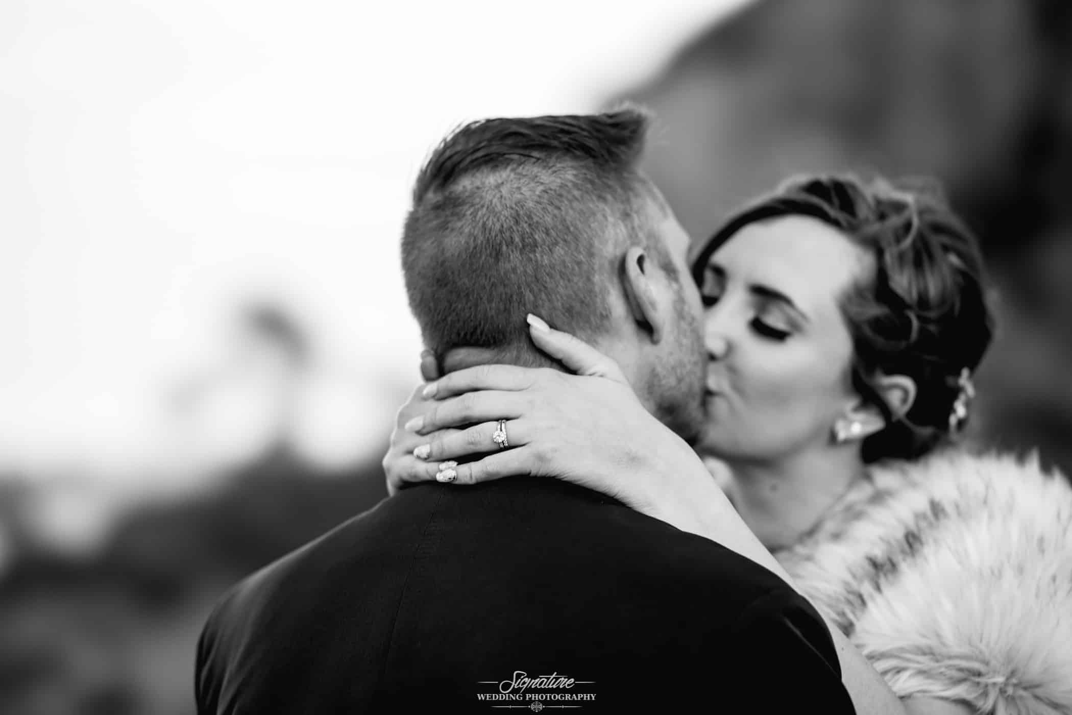 Close up of ring while bride and groom kiss black and white