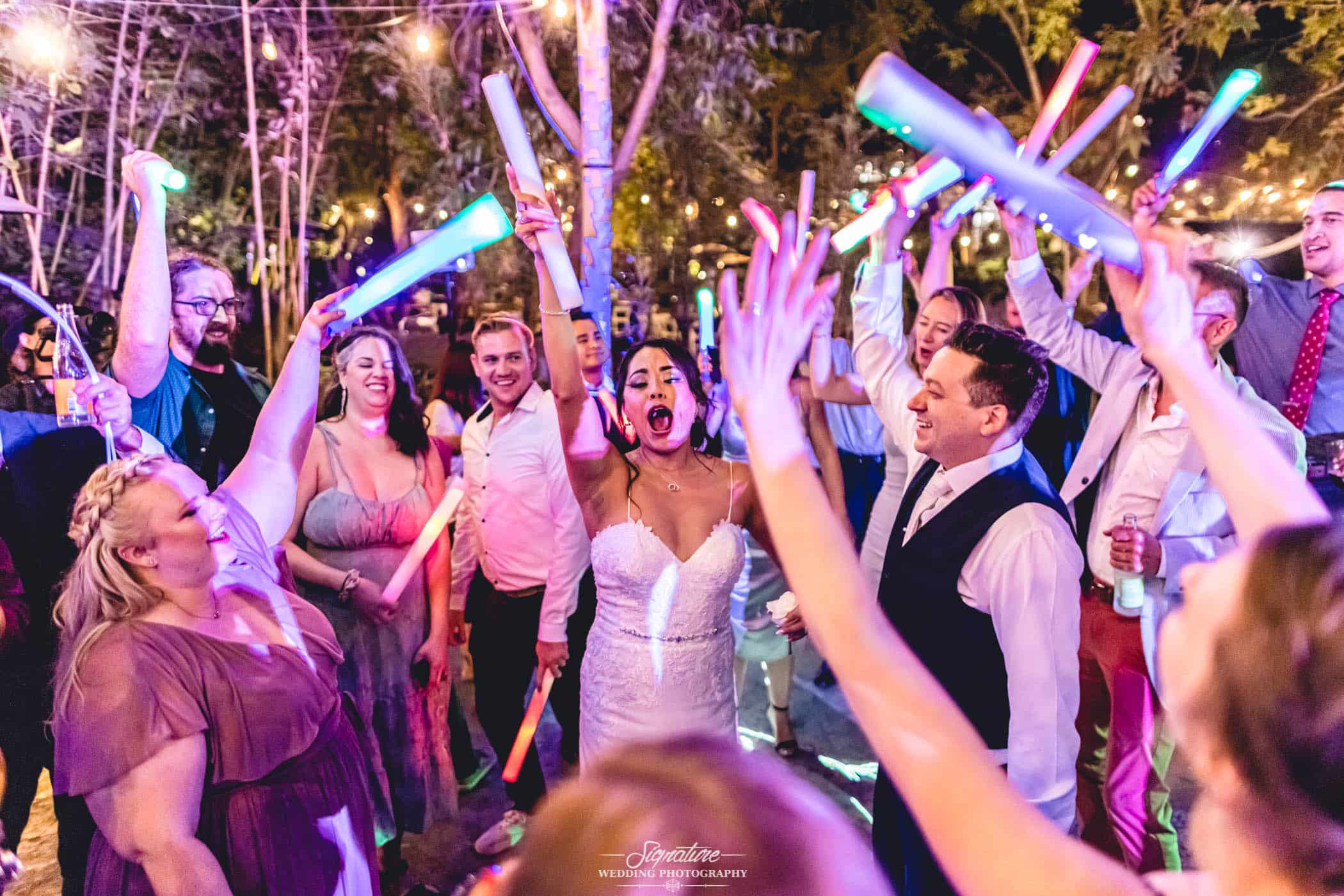 Bride and groom with guests holding light sticks