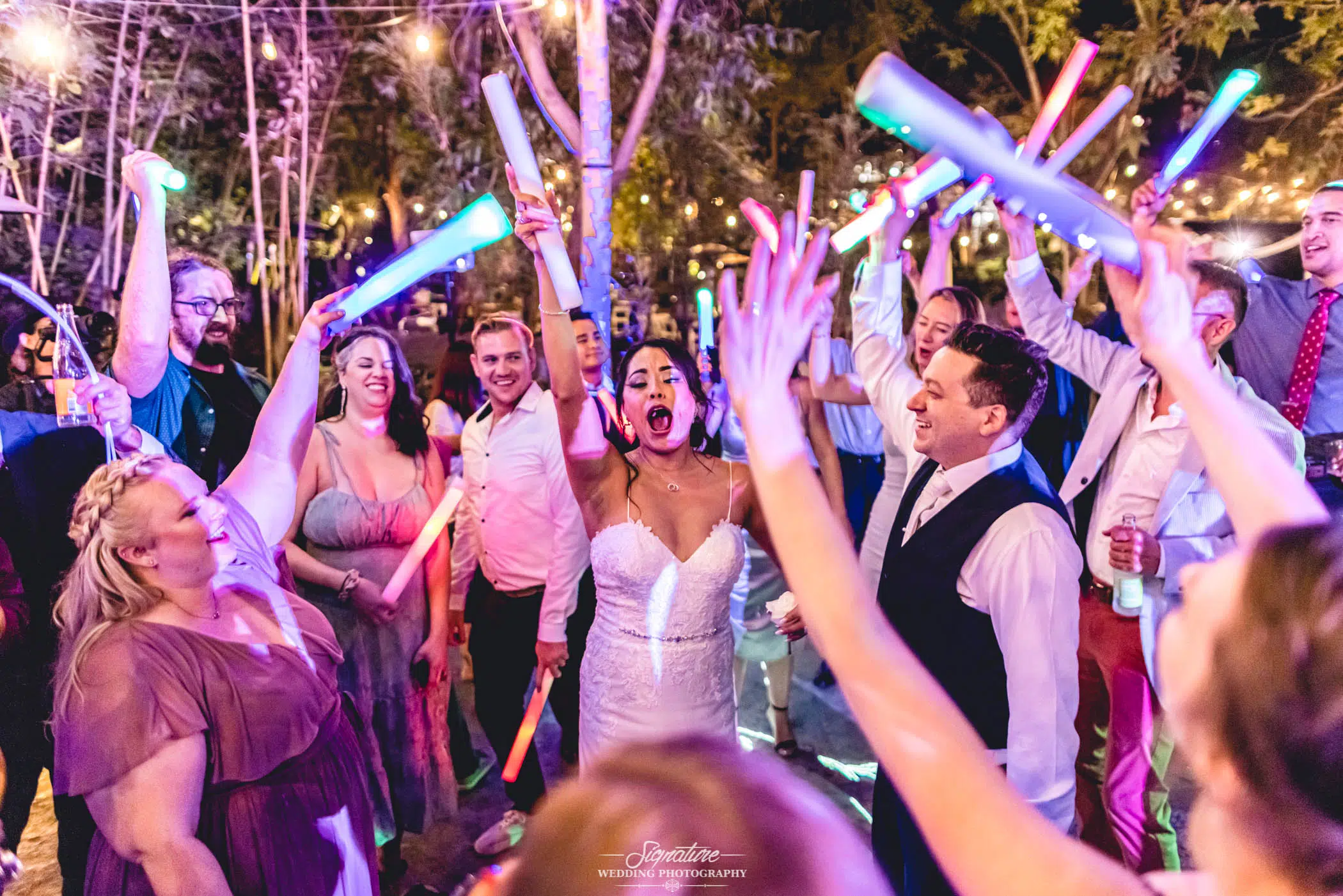 Bride and groom with guests holding light sticks