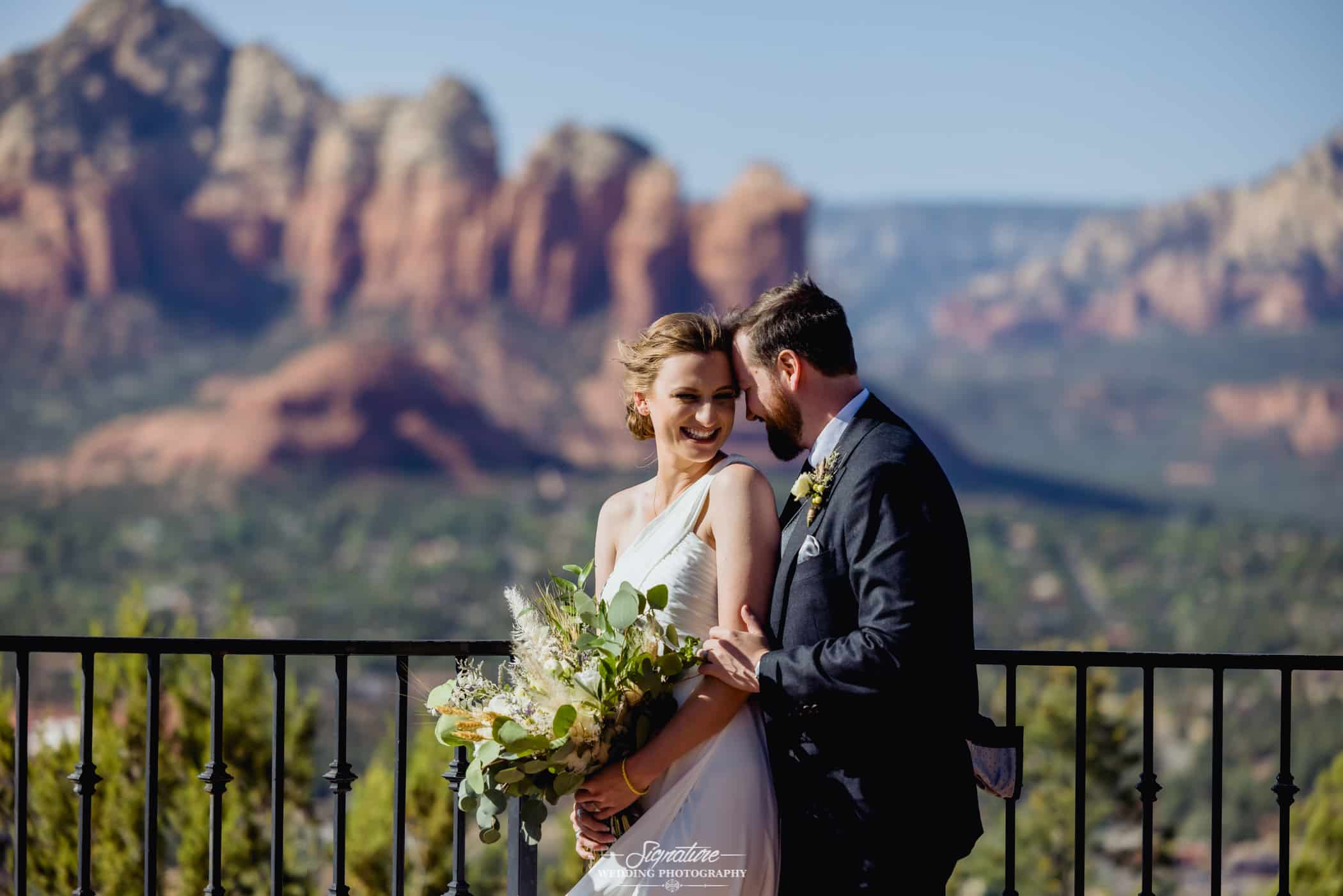 Bride and groom smiling in front of desert mountain range