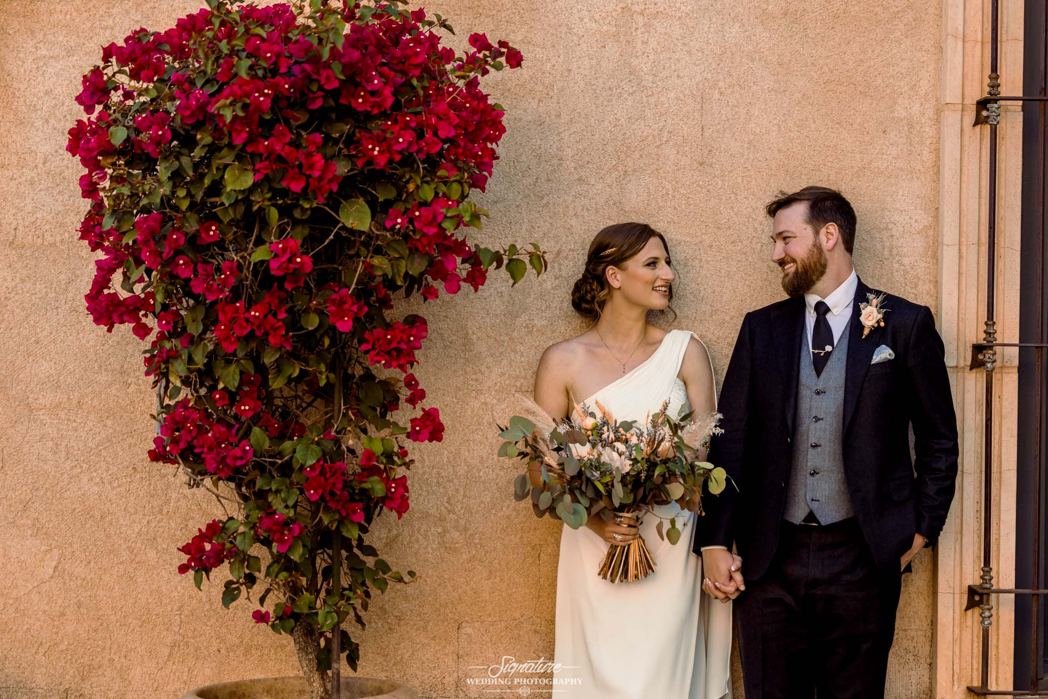 Bride and groom next to flowers smiling at each other