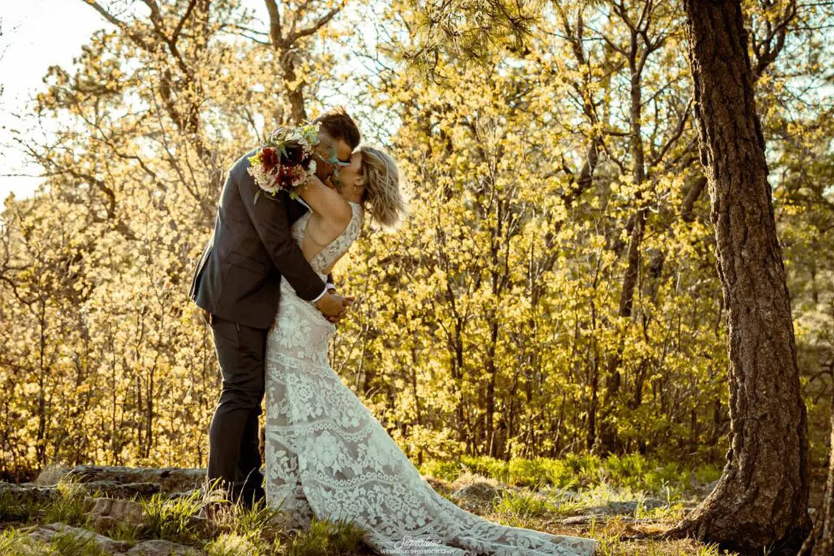 Bride and groom hugging and kissing in forest