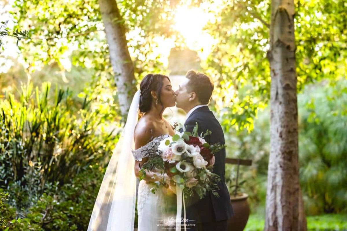 Bride and groom kissing with bouquet