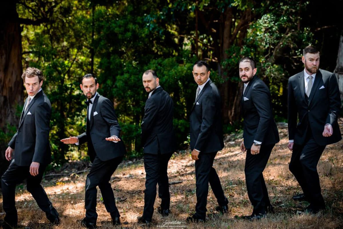 Groom with groomsmen doing funny pose in forest