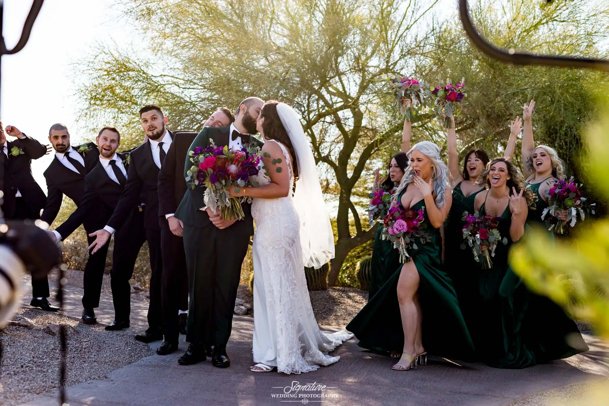 Bride and groom kissing in front of wedding party