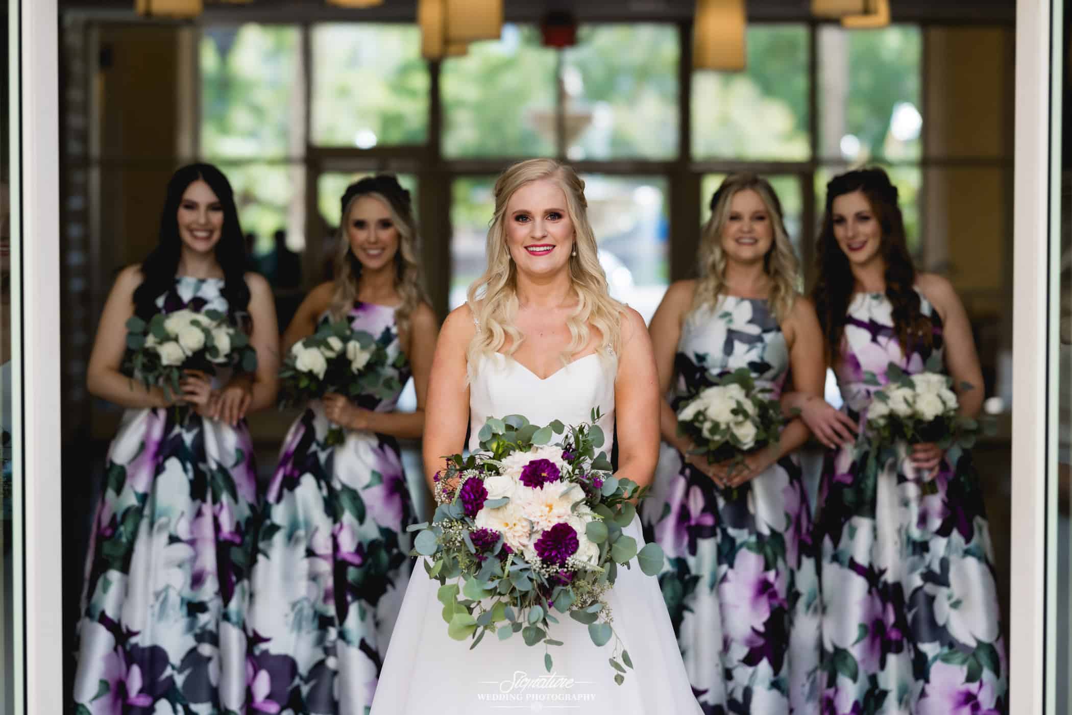 Bride smiling with bridesmaids behind her