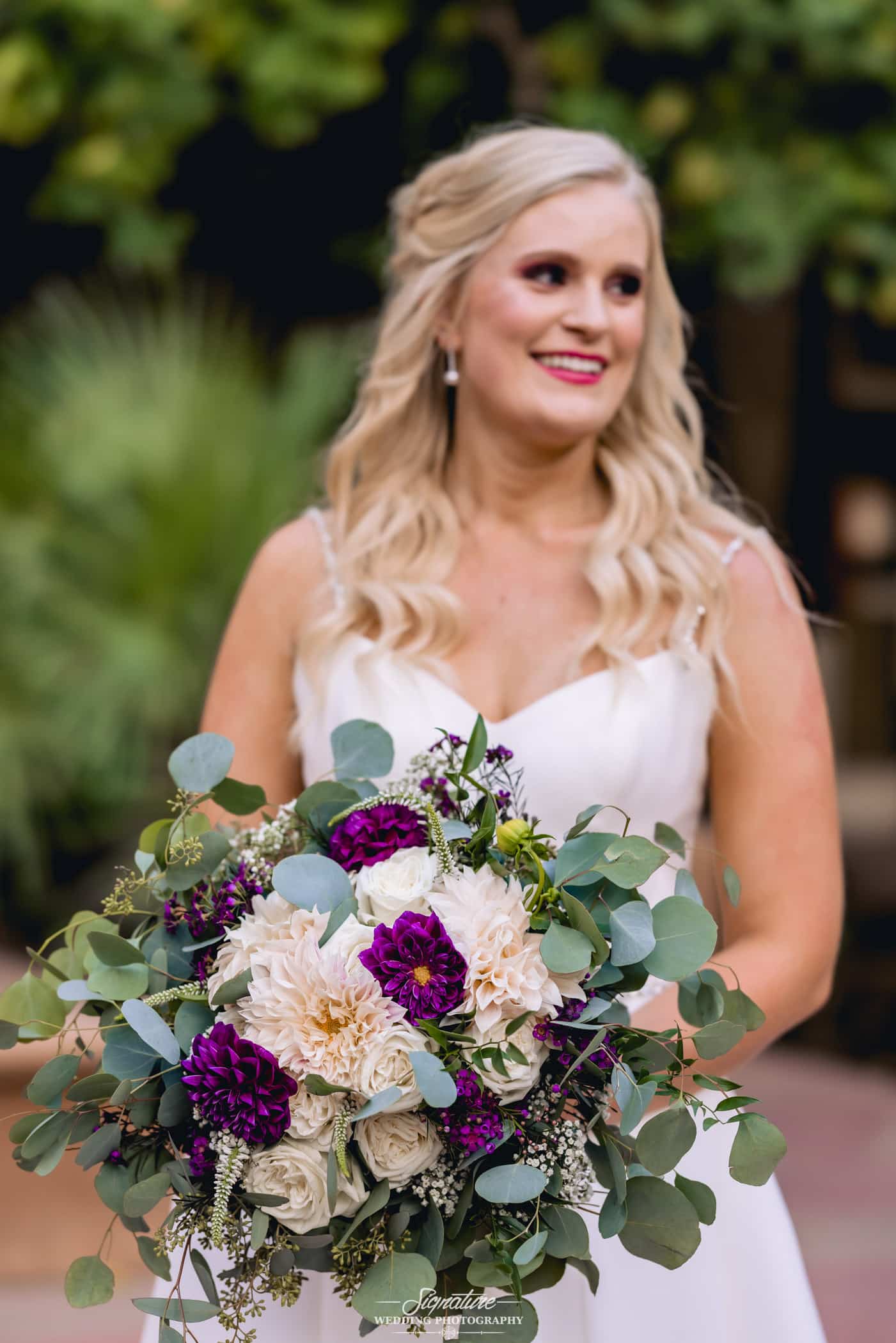 Bride smiling holding bouquet looking off camera
