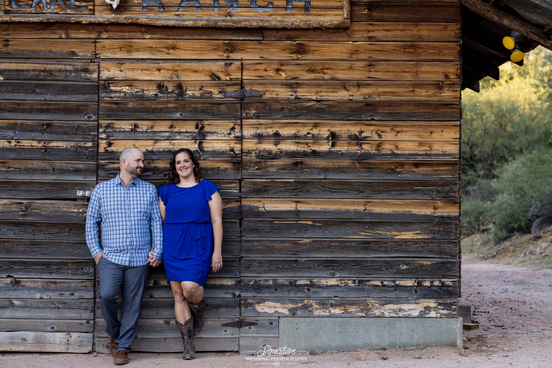 Couple holding hands smiling against wooden barn