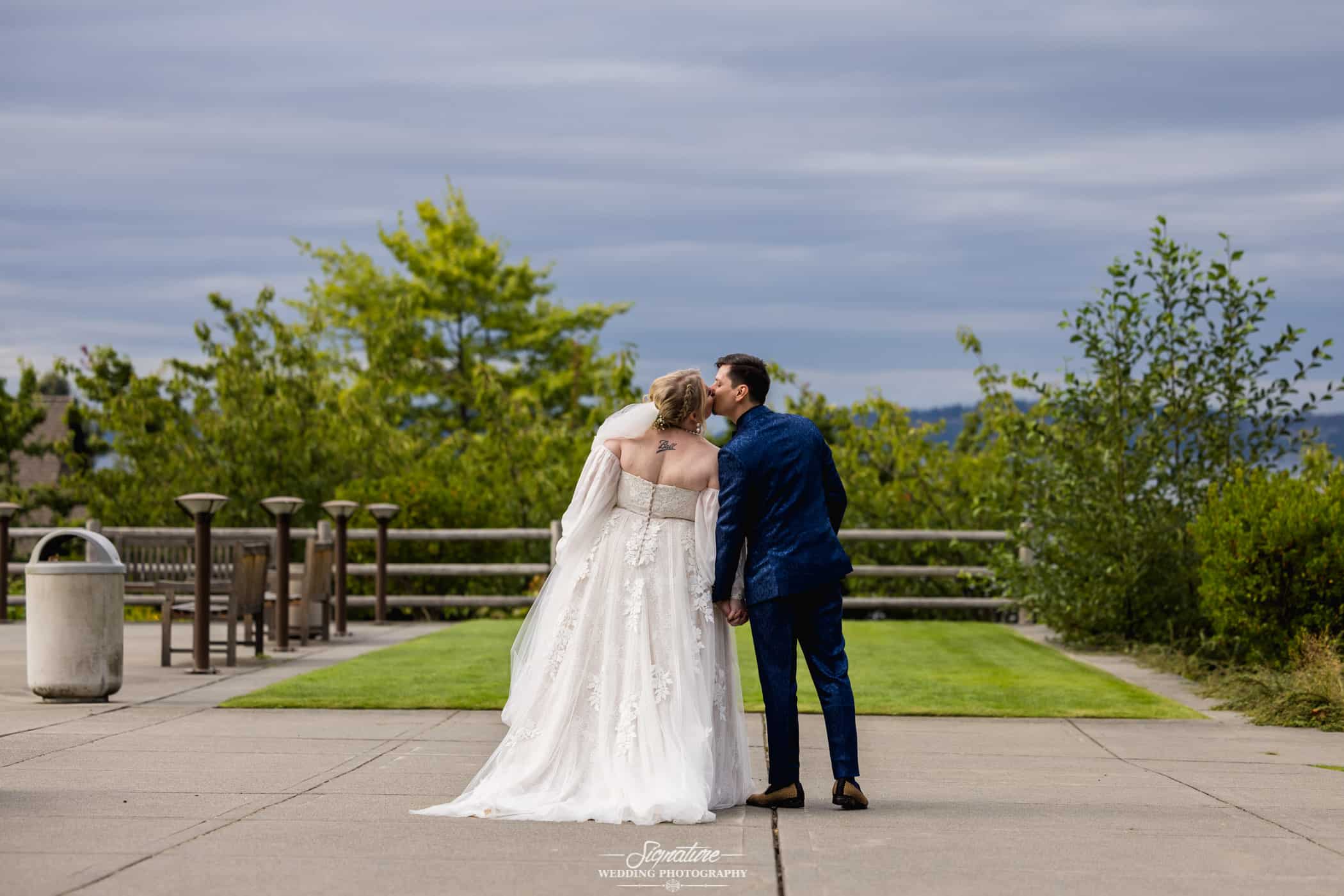 Bride and groom facing away from camera kissing