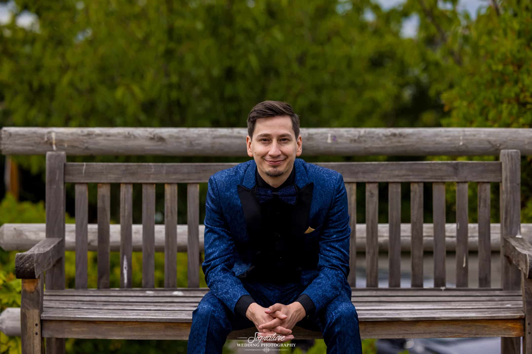 Groom sitting on bench smiling