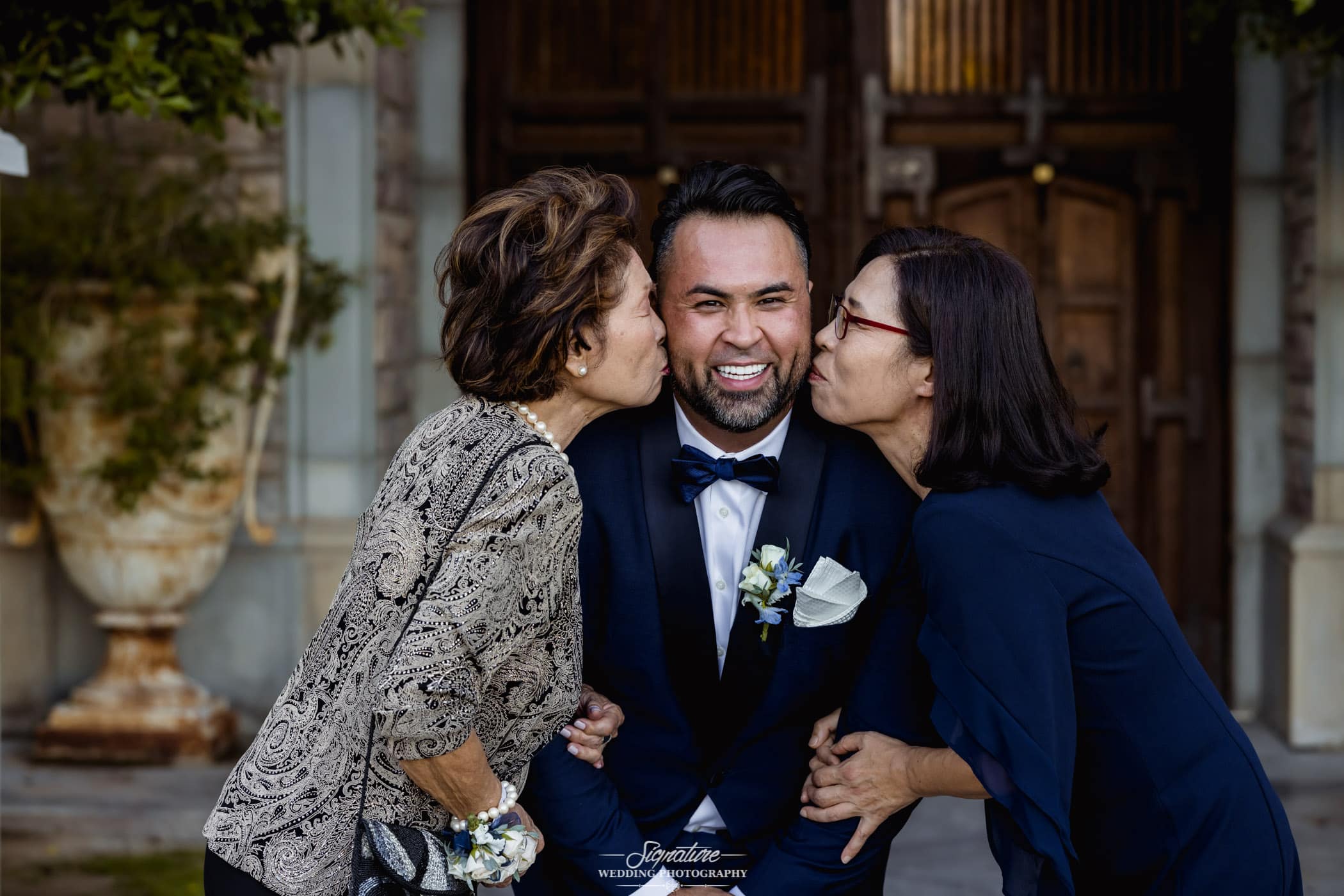 Moms kissing groom's cheeks
