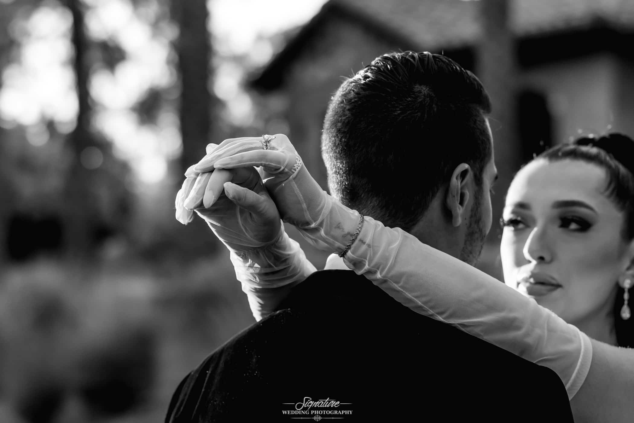 Bride's arms around groom's neck black and white