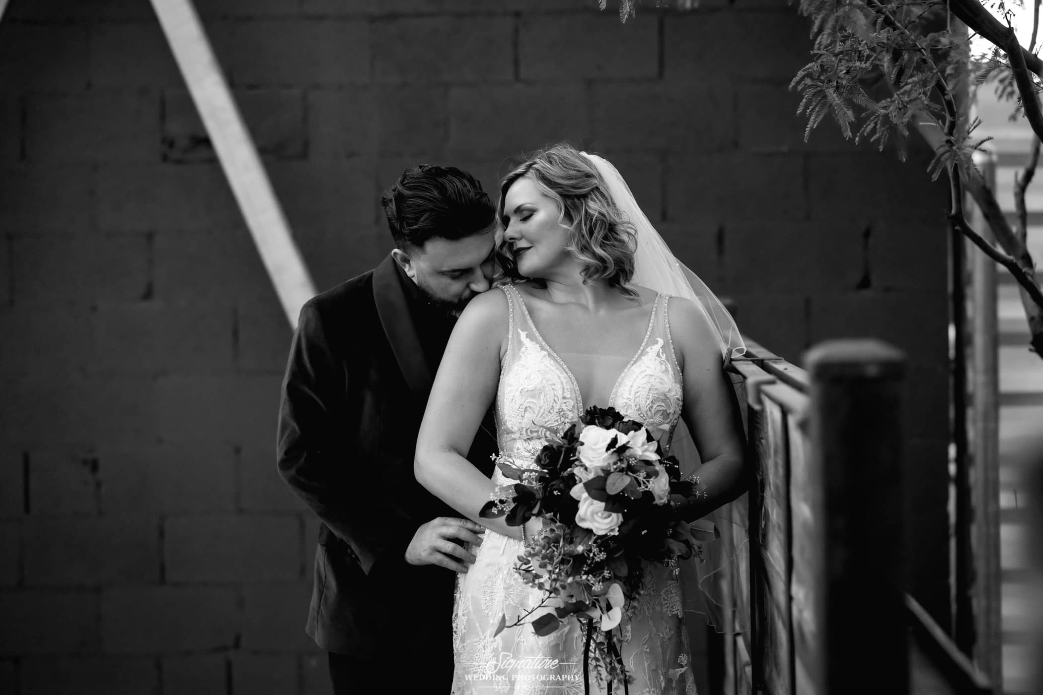 Groom kissing bride's shoulder black and white