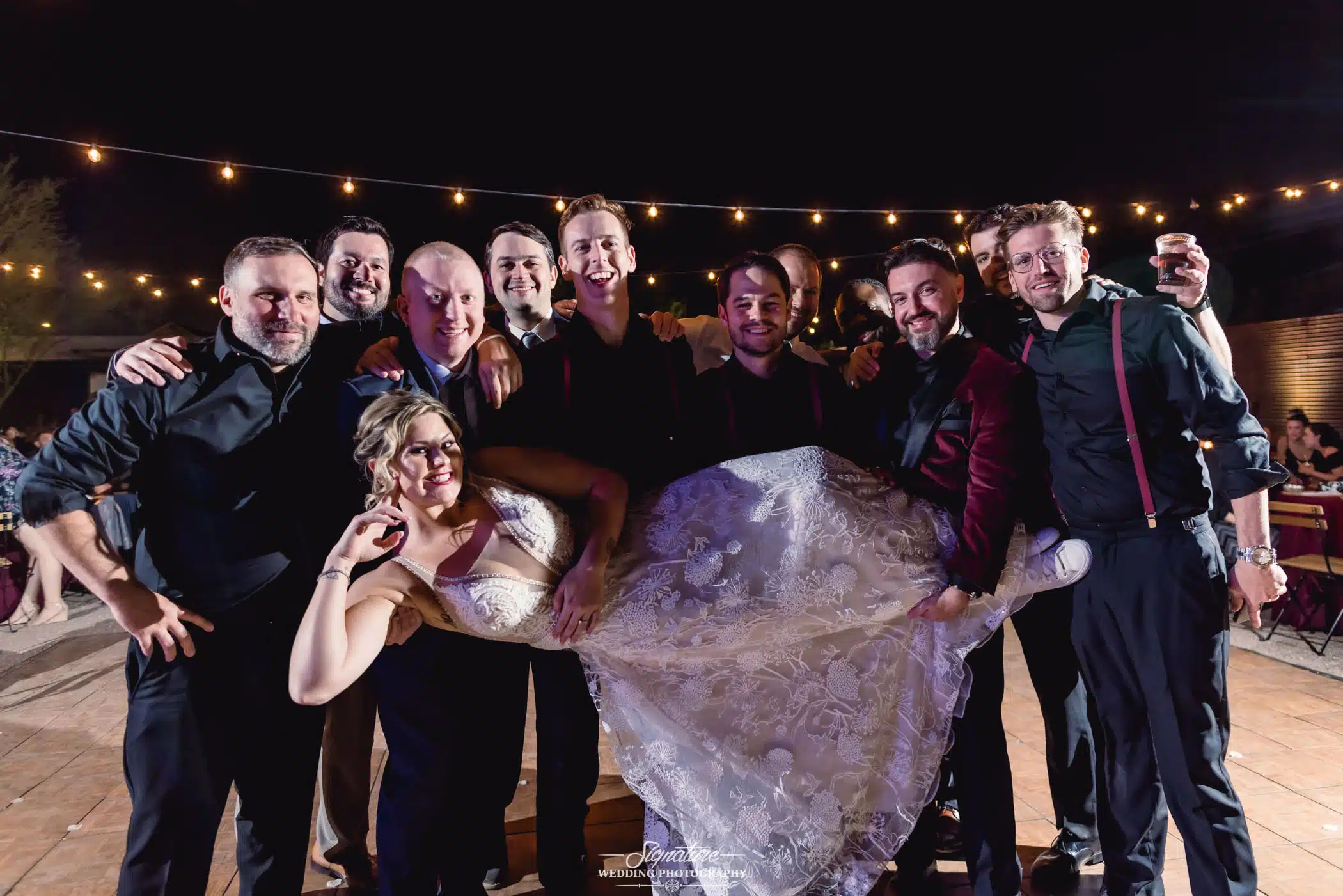 Groom and groomsmen holding up bride