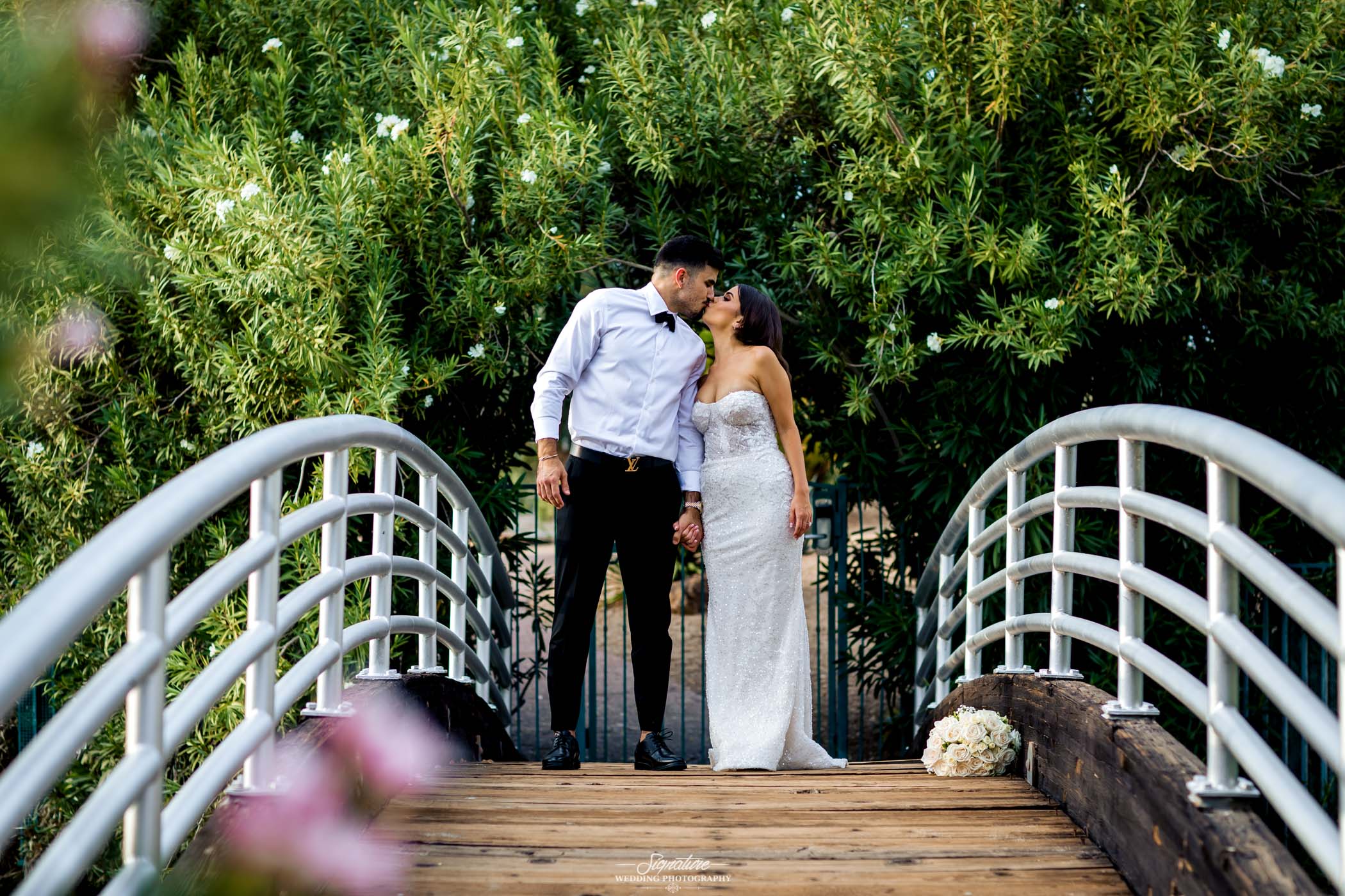 Bride and groom kissing on bridge