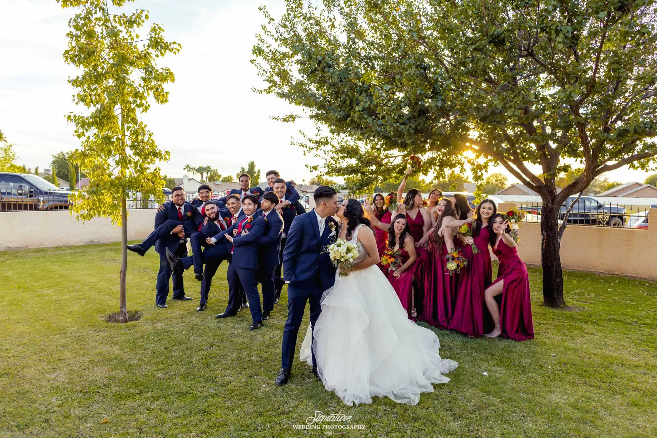 Bride and groom kissing in front of wedding party