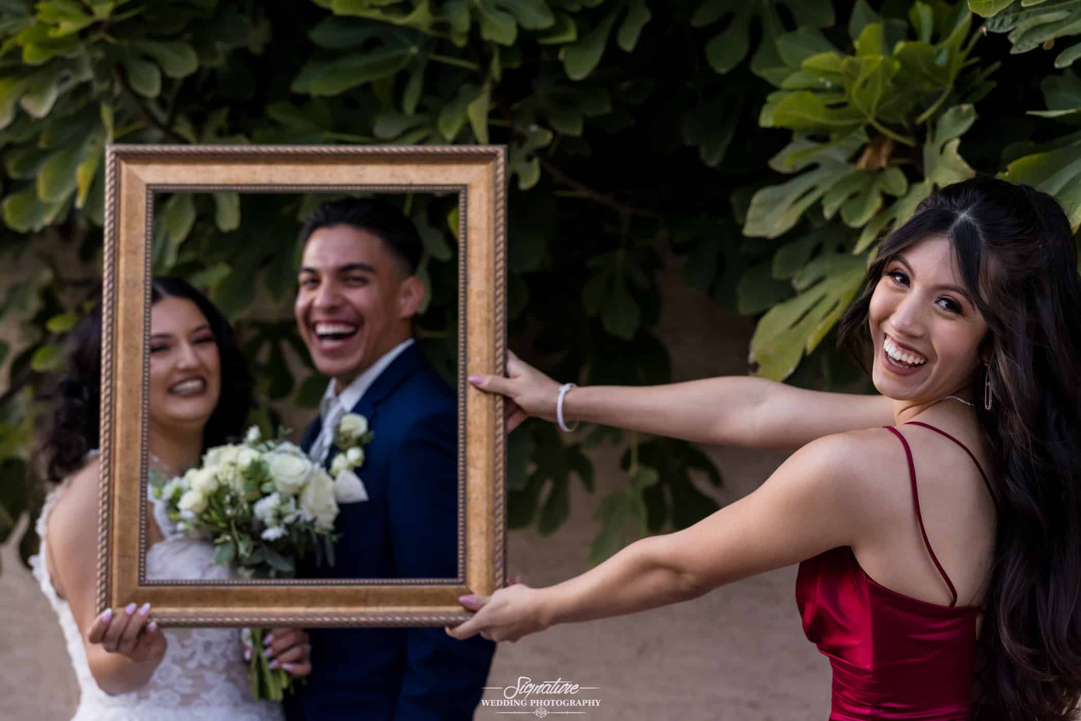 Bridesmaid holding frame around bride and groom