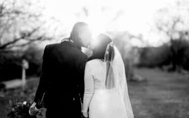 Bride and groom kissing facing away from camera black and white