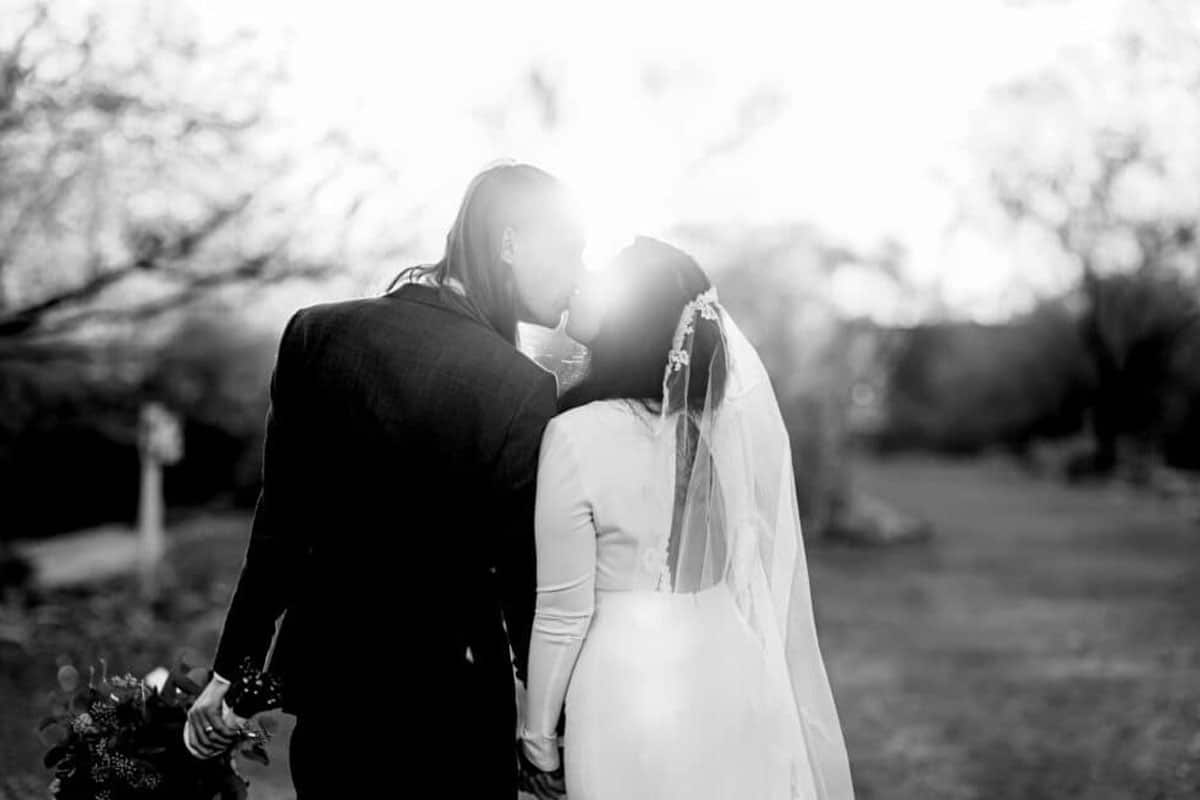 Bride and groom kissing facing away from camera black and white