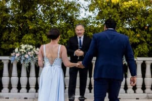 Bride and groom holding hands in front of officiant