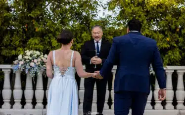 Bride and groom holding hands in front of officiant