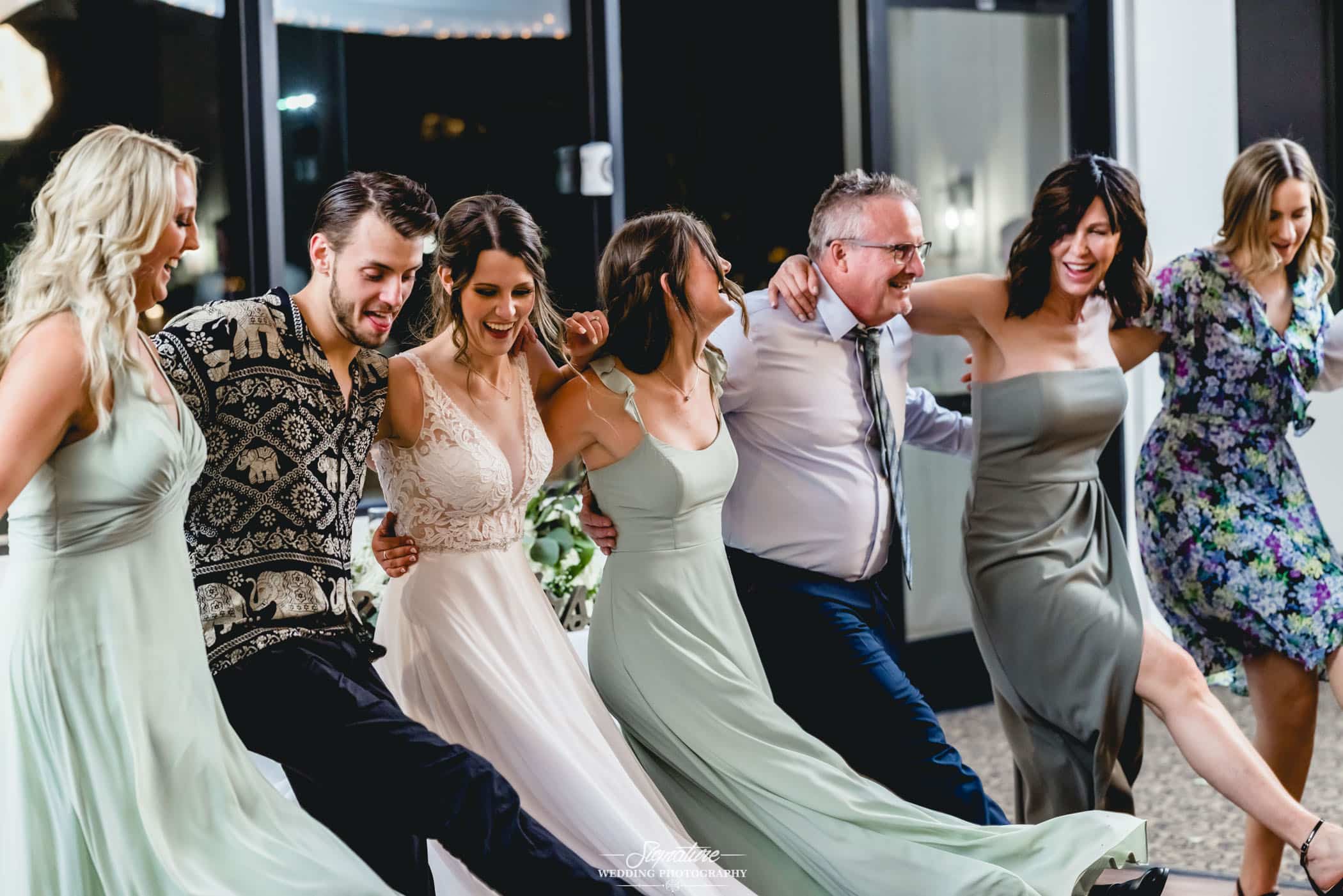 Bride doing kickline dance with wedding guests