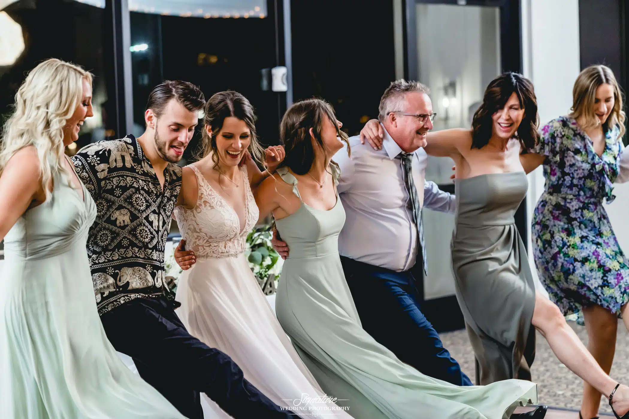 Image by Signature Wedding Photography Bride doing kickline dance with wedding guests