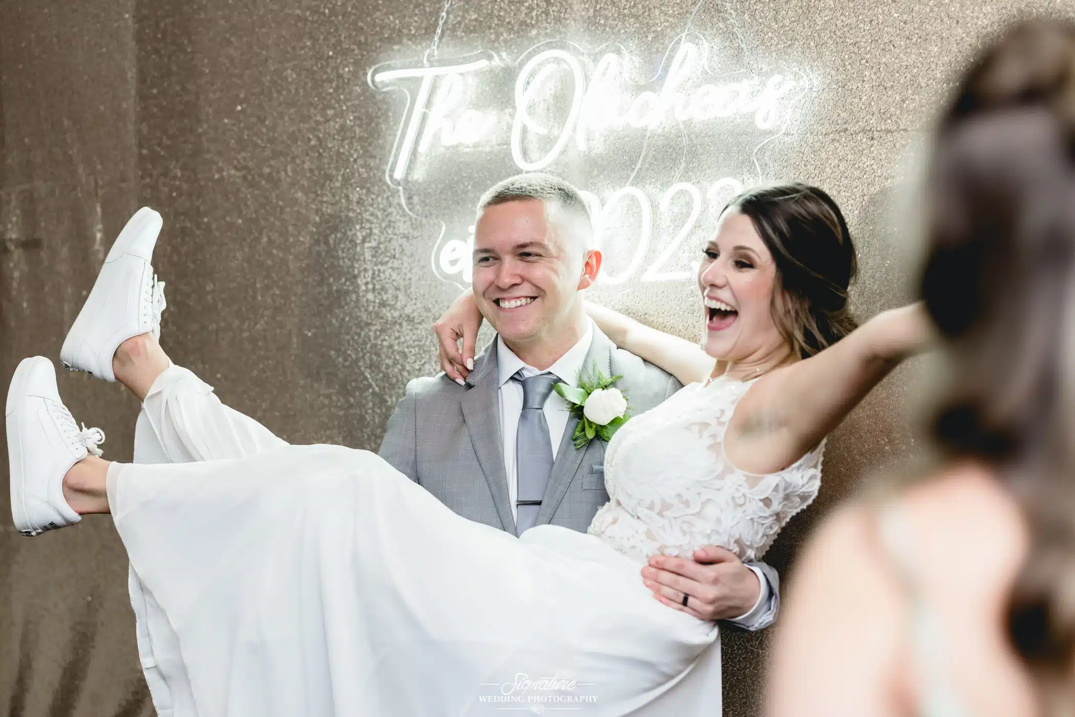 Image by Signature Wedding Photography Groom holding bride for photo booth