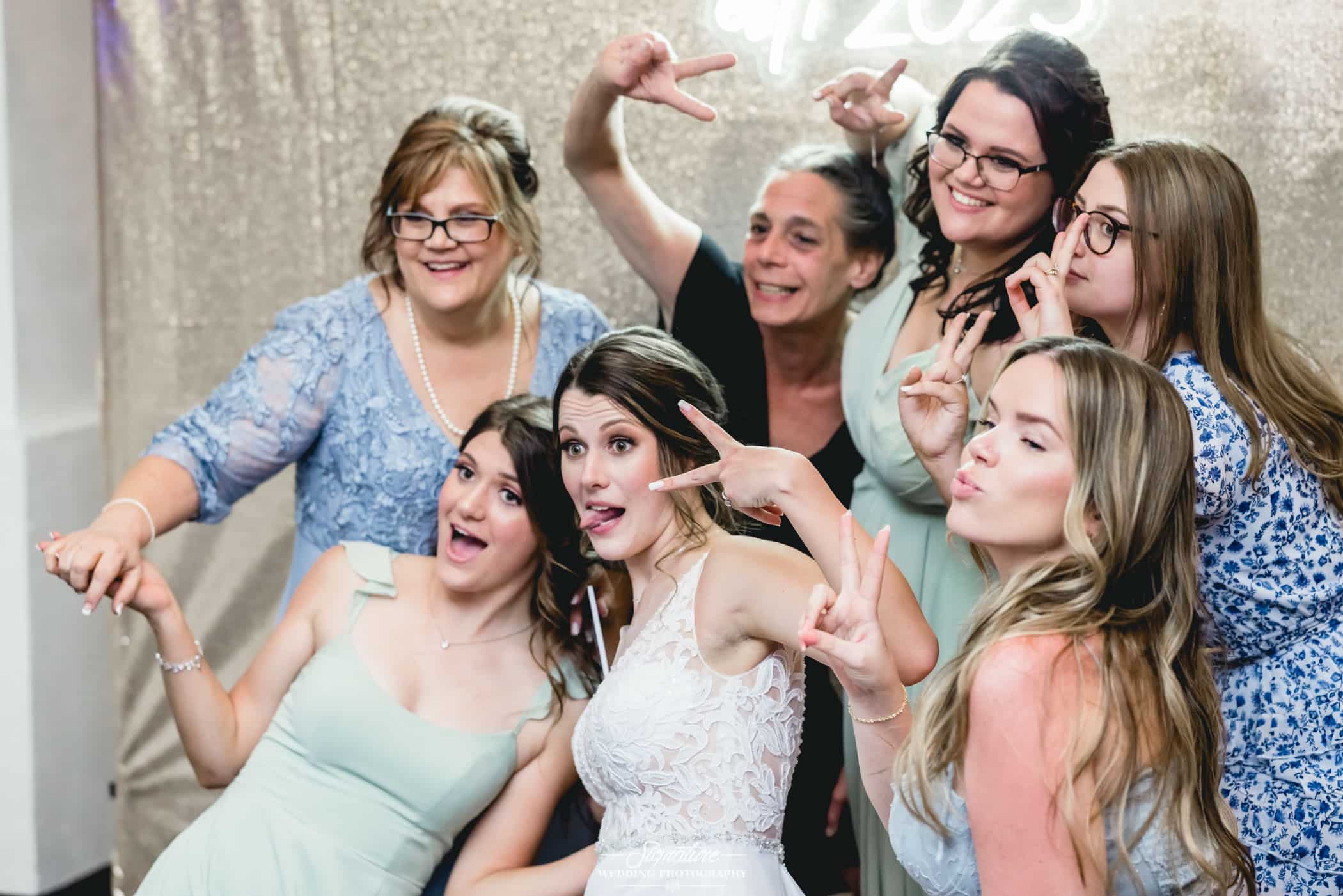 Bride posing with wedding guests for photo booth