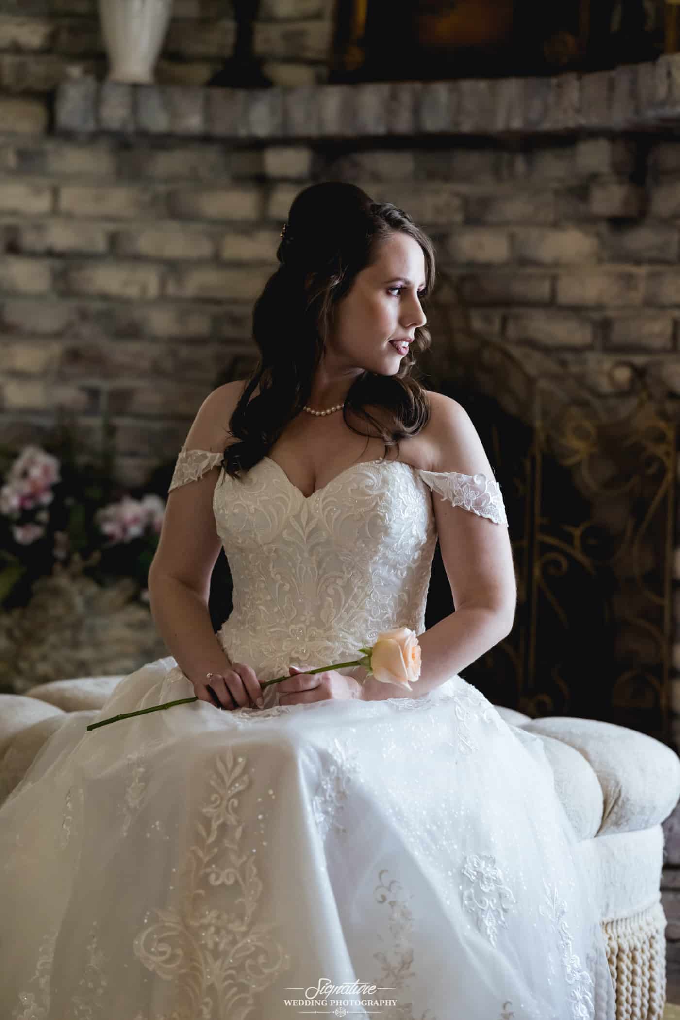 Bride sitting holding flower looking to side