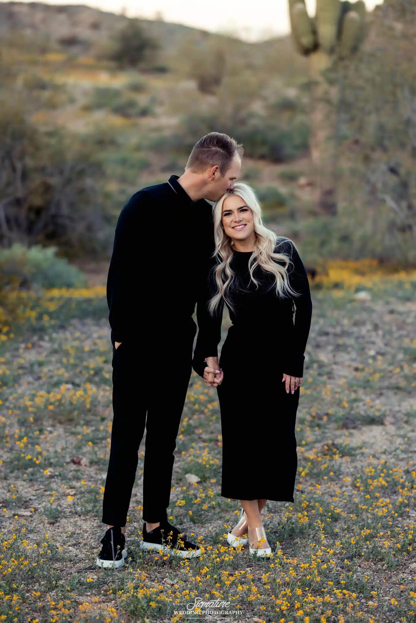 Image by Signature Wedding Photography Man kissing woman's forehead in desert engagement shoot