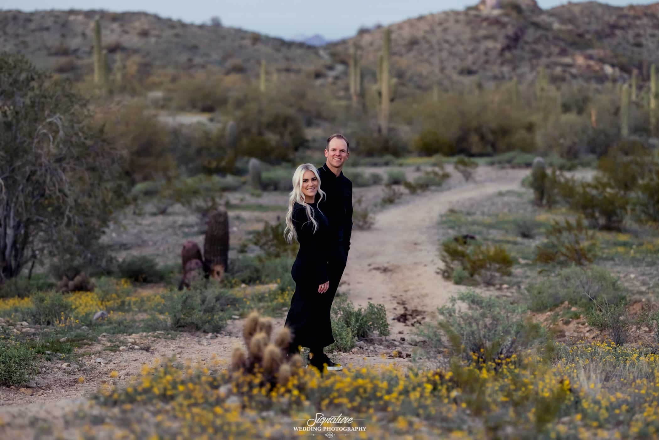 Couple smiling at camera on desert path