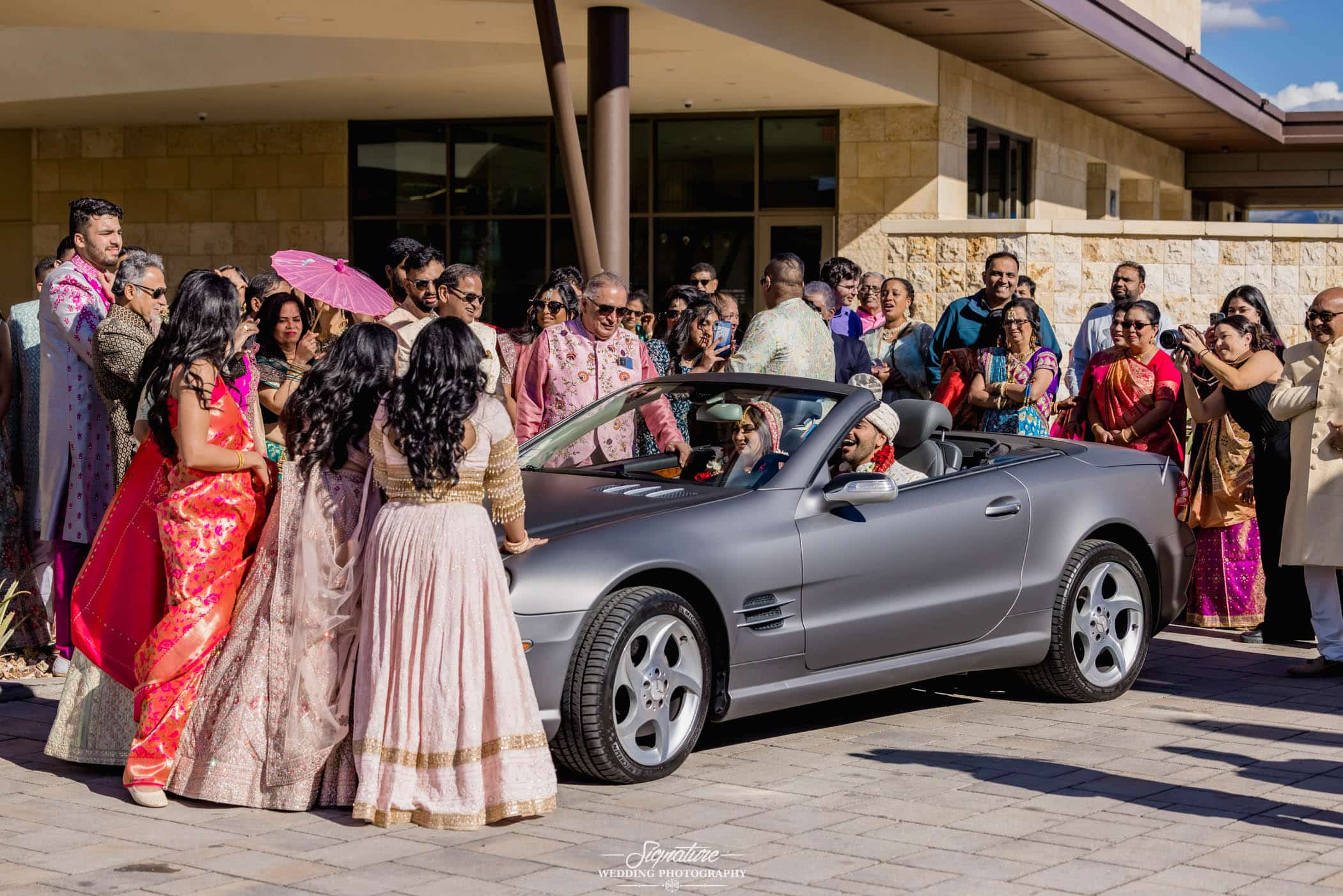 Wedding guests waving at bride and groom in car