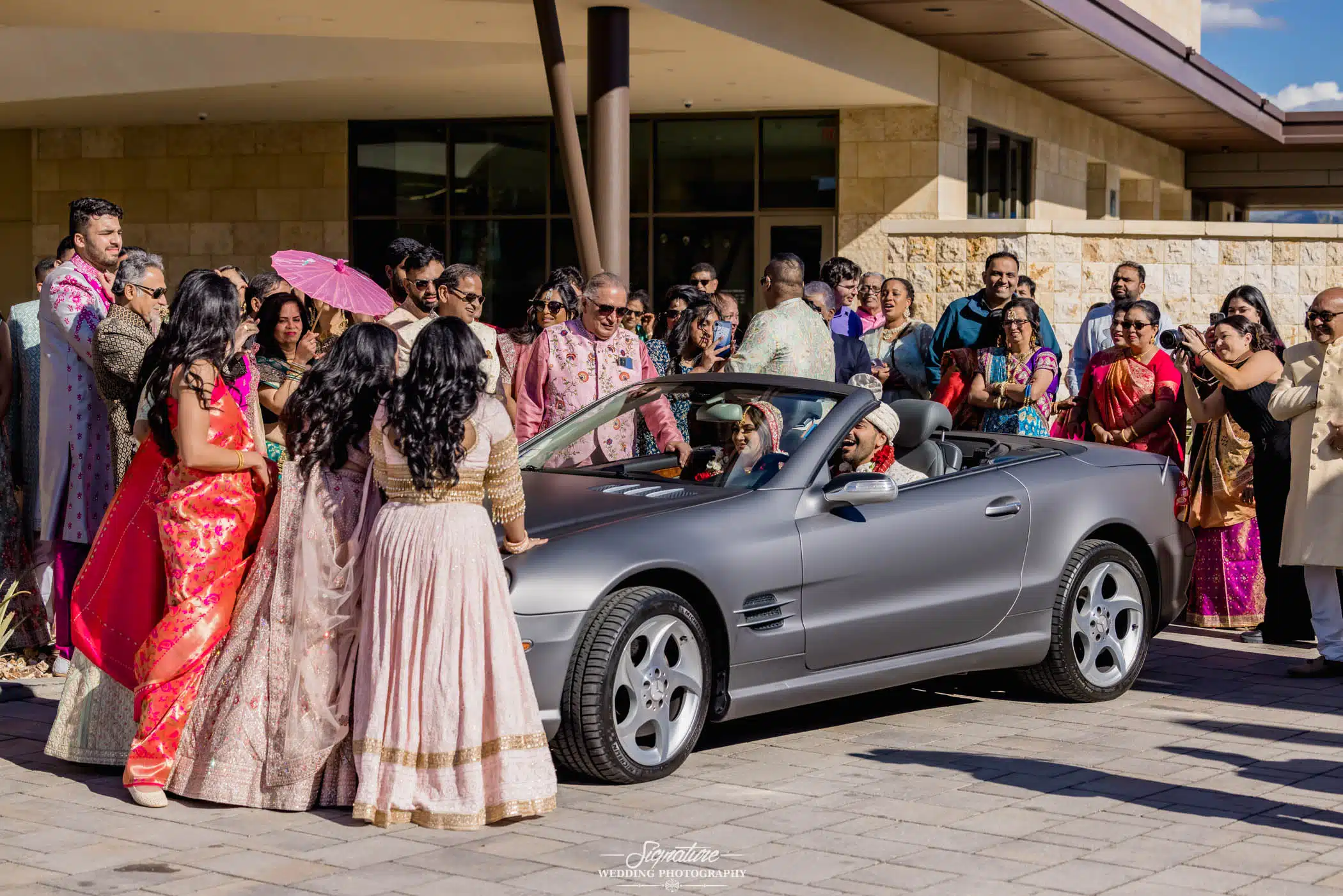 Image by Signature Wedding Photography Wedding guests waving at bride and groom in car