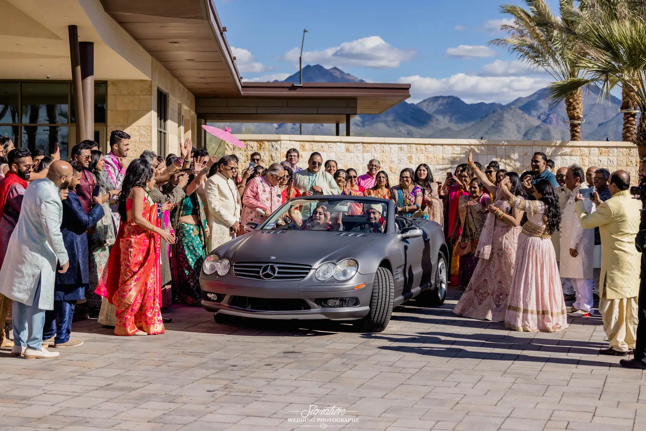 Image by Signature Wedding Photography Wedding guests waving at bride and groom in car