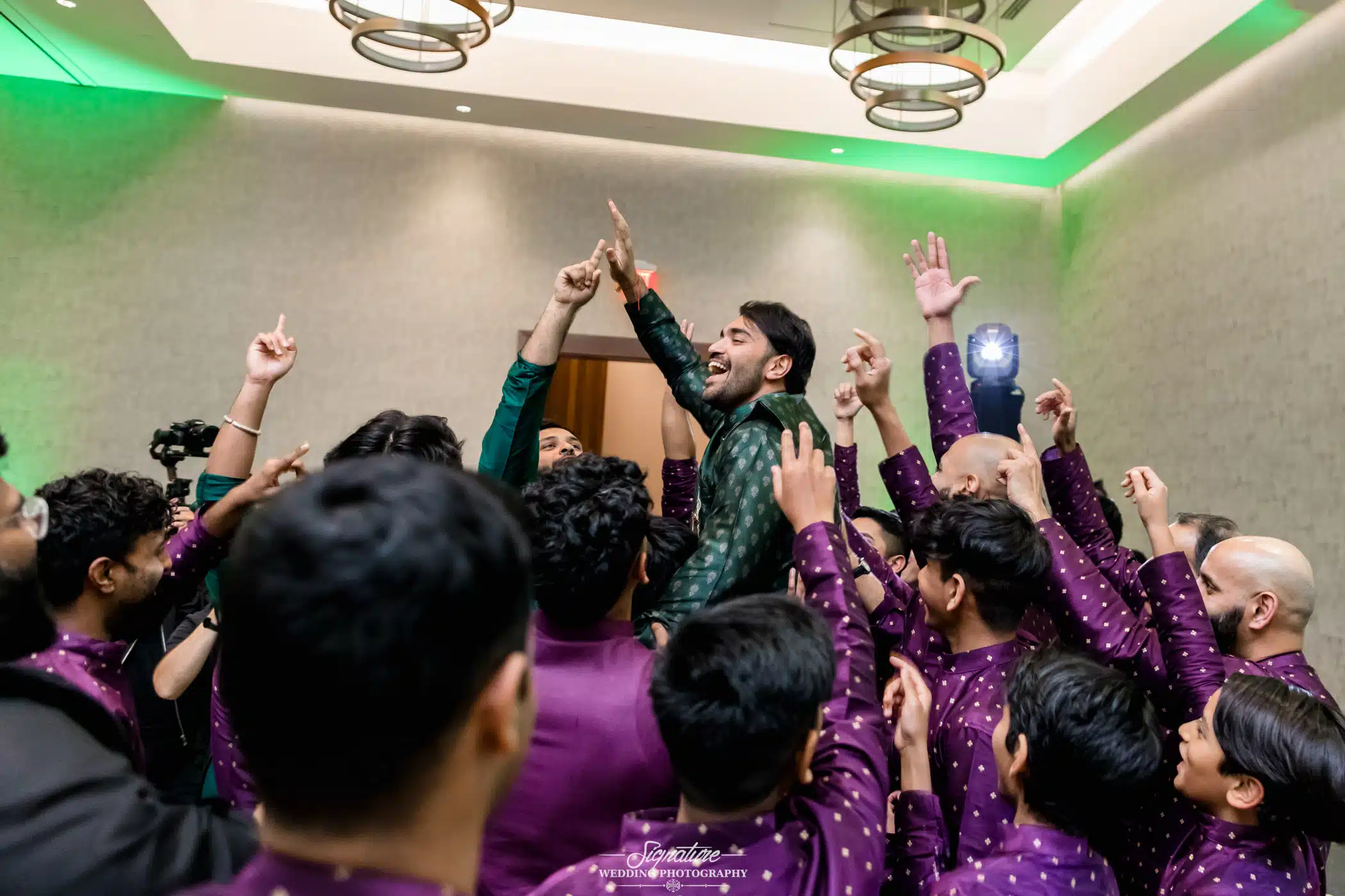 Image by Signature Wedding Photography Groomsmen picking up groom