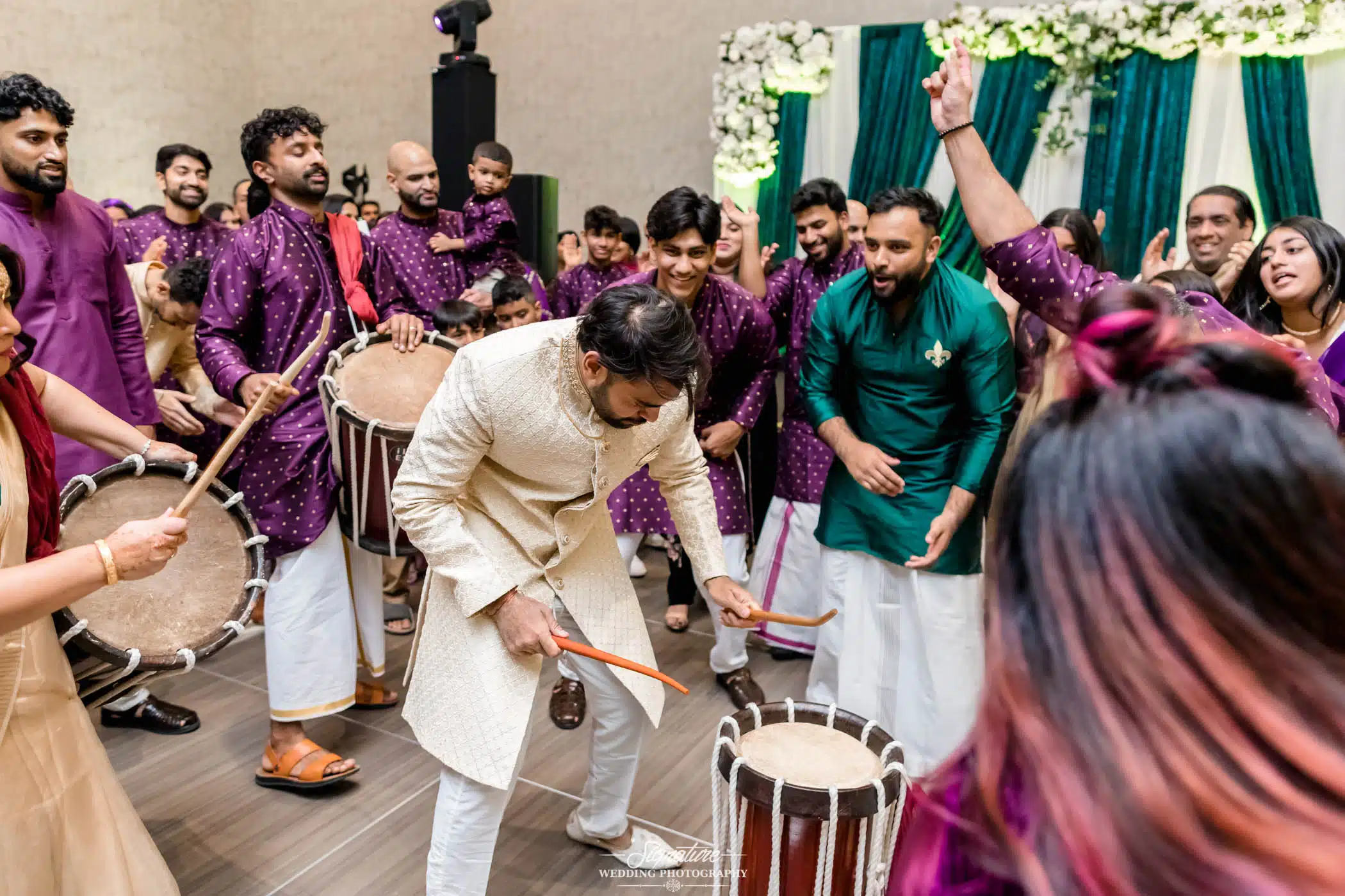 Image by Signature Wedding Photography Groom playing drums in drum circle