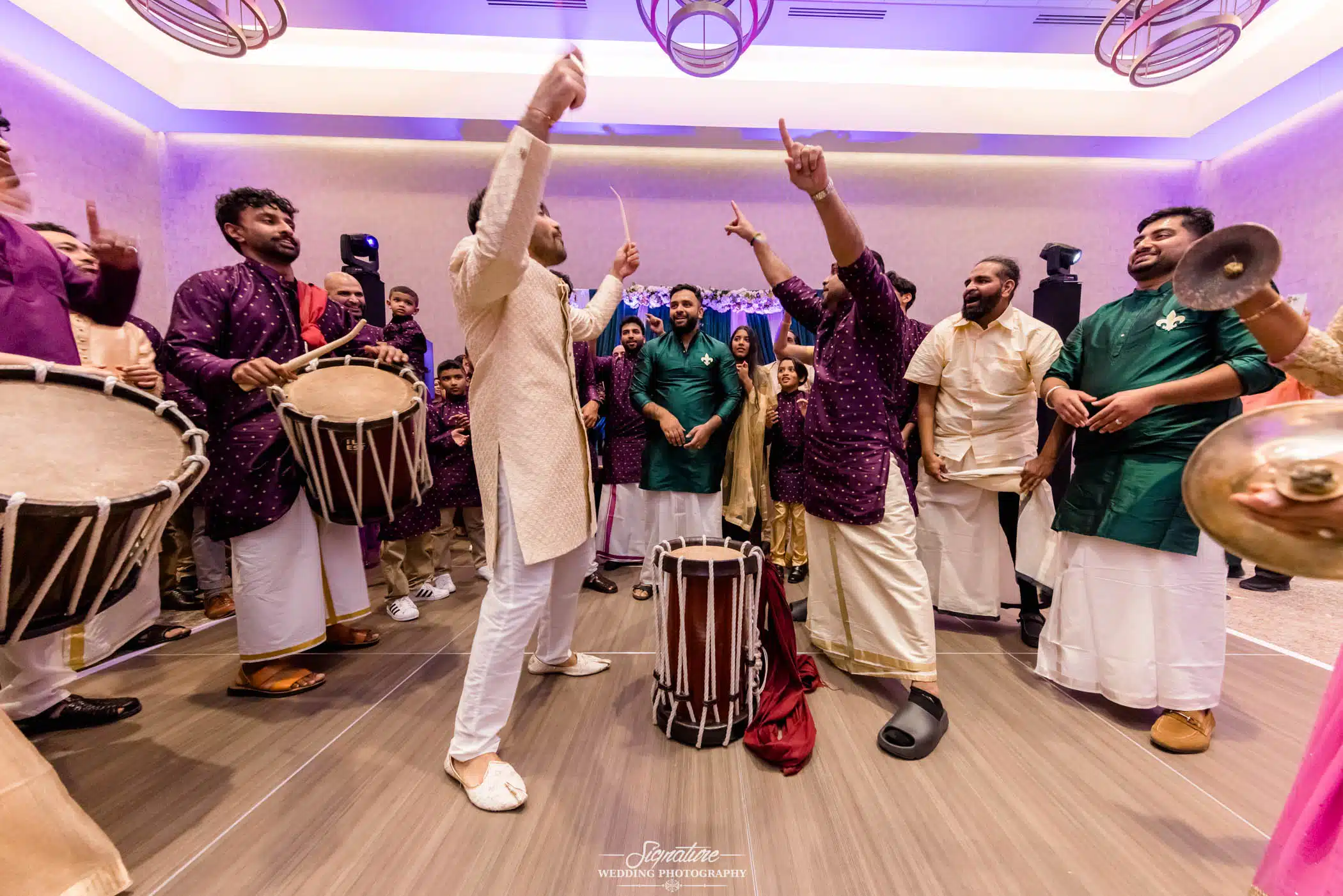 Image by Signature Wedding Photography Groom with arms up in drum circle